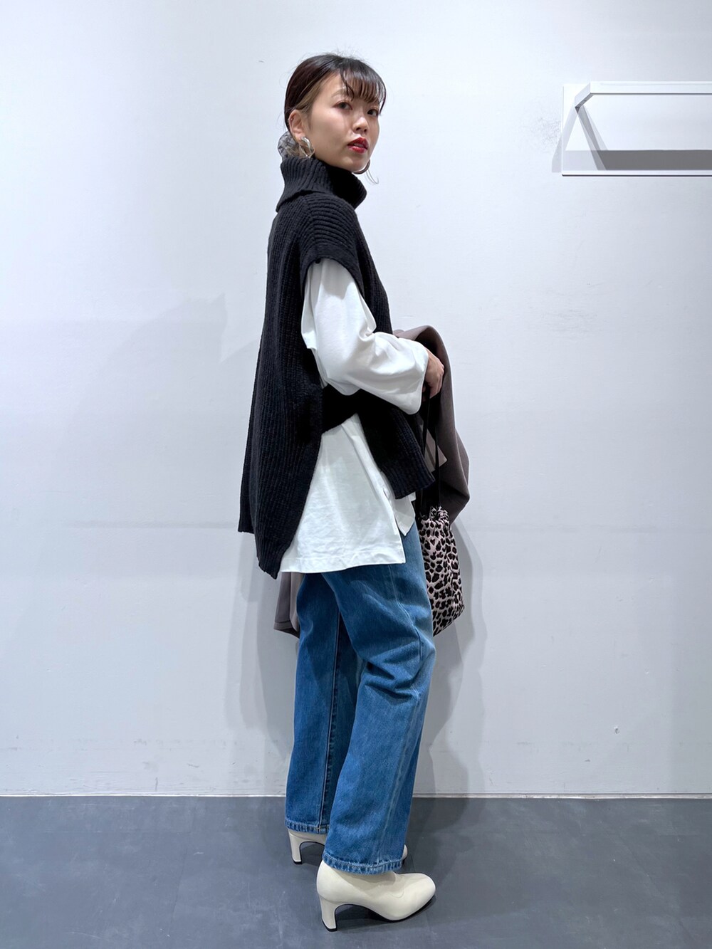 ブラック系のバッグ、ホワイト系のブーツ、ブルー系のデニムパンツを着用したレディースの冬コーディネートの3枚目の写真