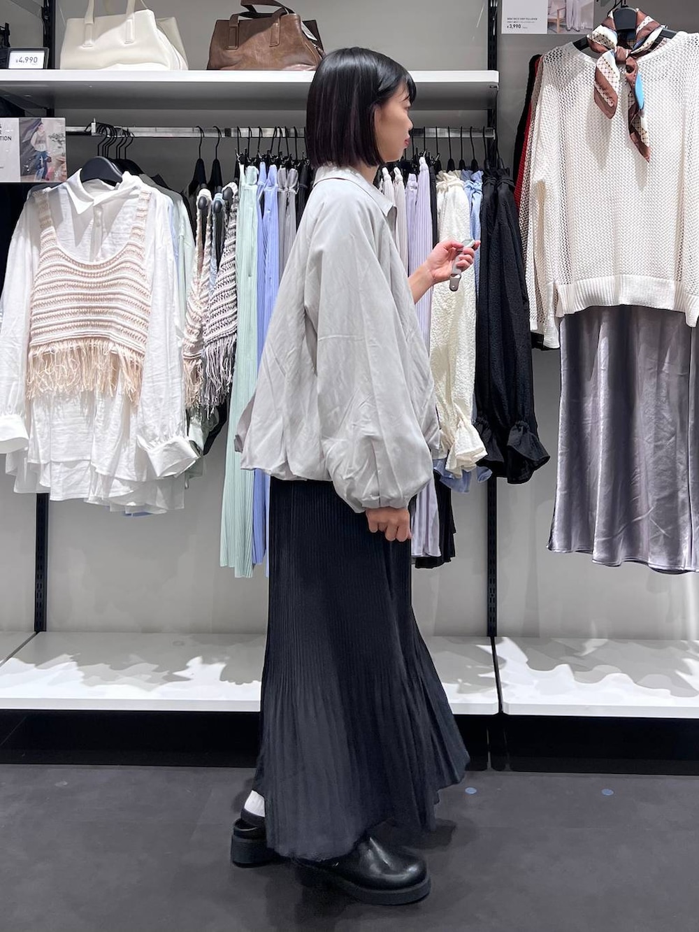 ブラック系のボストンバッグ、ブラック系のサンダル、グレー系のブルゾンを着用したレディースの春コーディネートの3枚目の写真