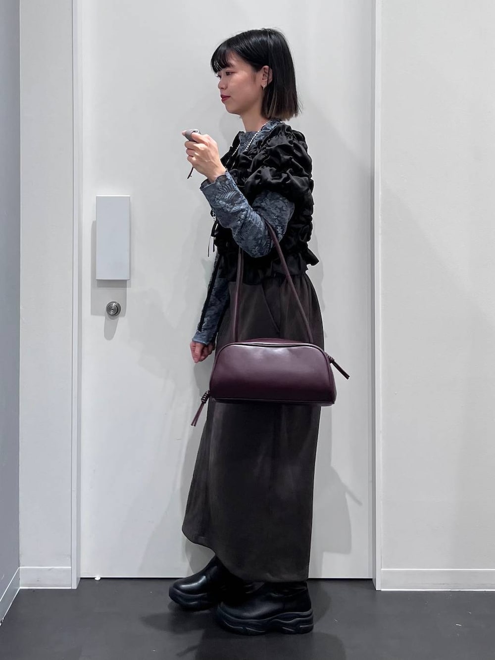 グレー系のスカート、ブラック系のシャツ/ブラウス、レッド系のボストンバッグを着用したレディースの秋コーディネートの4枚目の写真