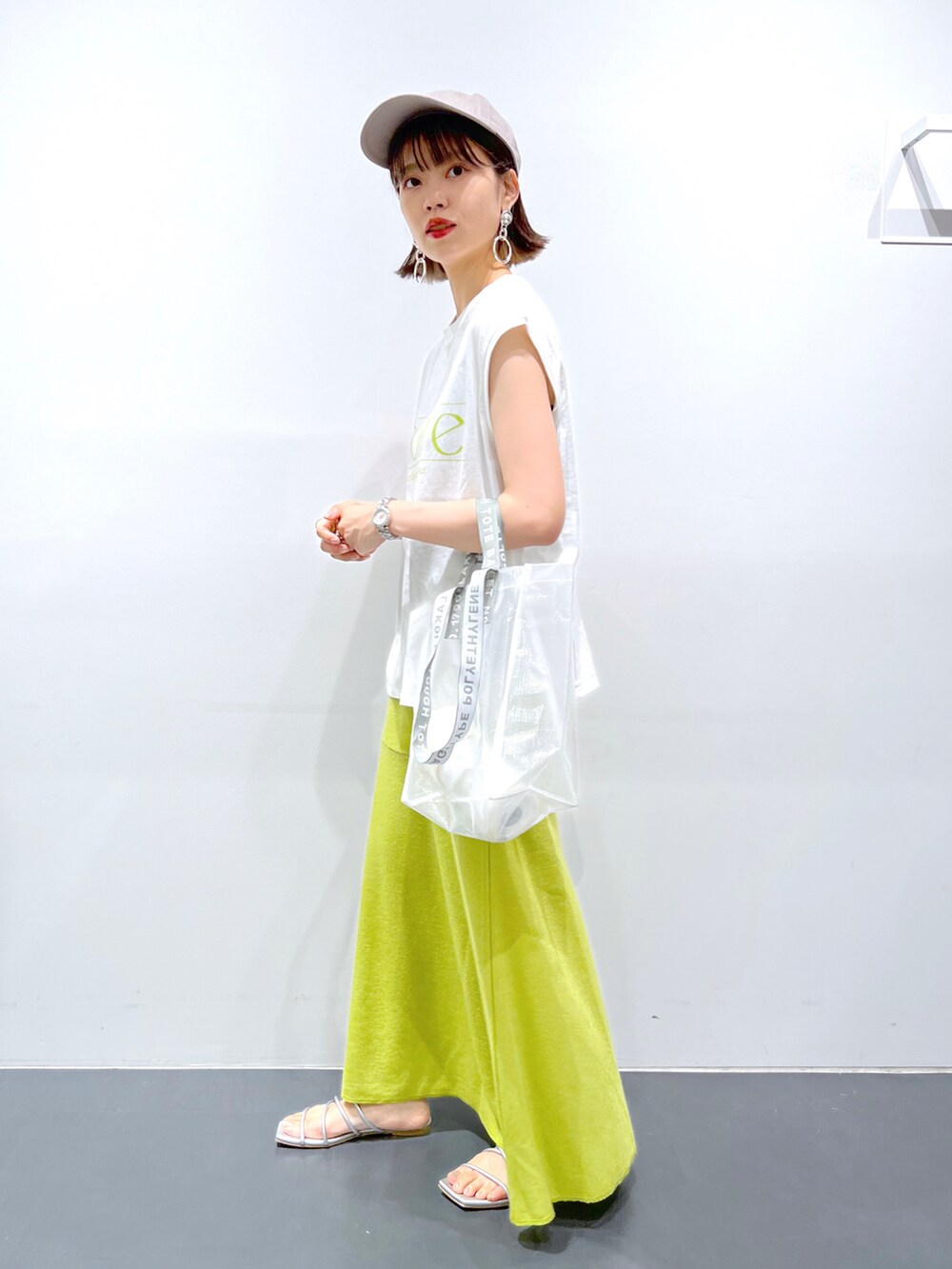 グリーン系のスカート、グリーン系のエコバッグ/サブバッグ、ホワイト系のTシャツ/カットソーを着用したレディースの夏コーディネートの2枚目の写真