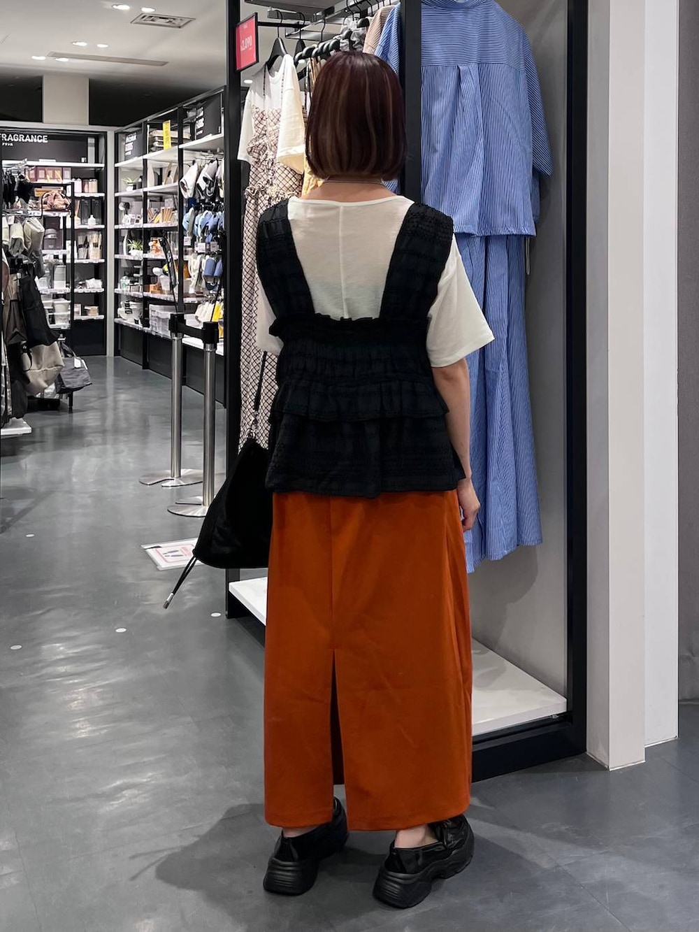 ホワイト系のTシャツ/カットソー、オレンジ系のスカート、ブラック系のローファーを着用したレディースの夏コーディネートの4枚目の写真