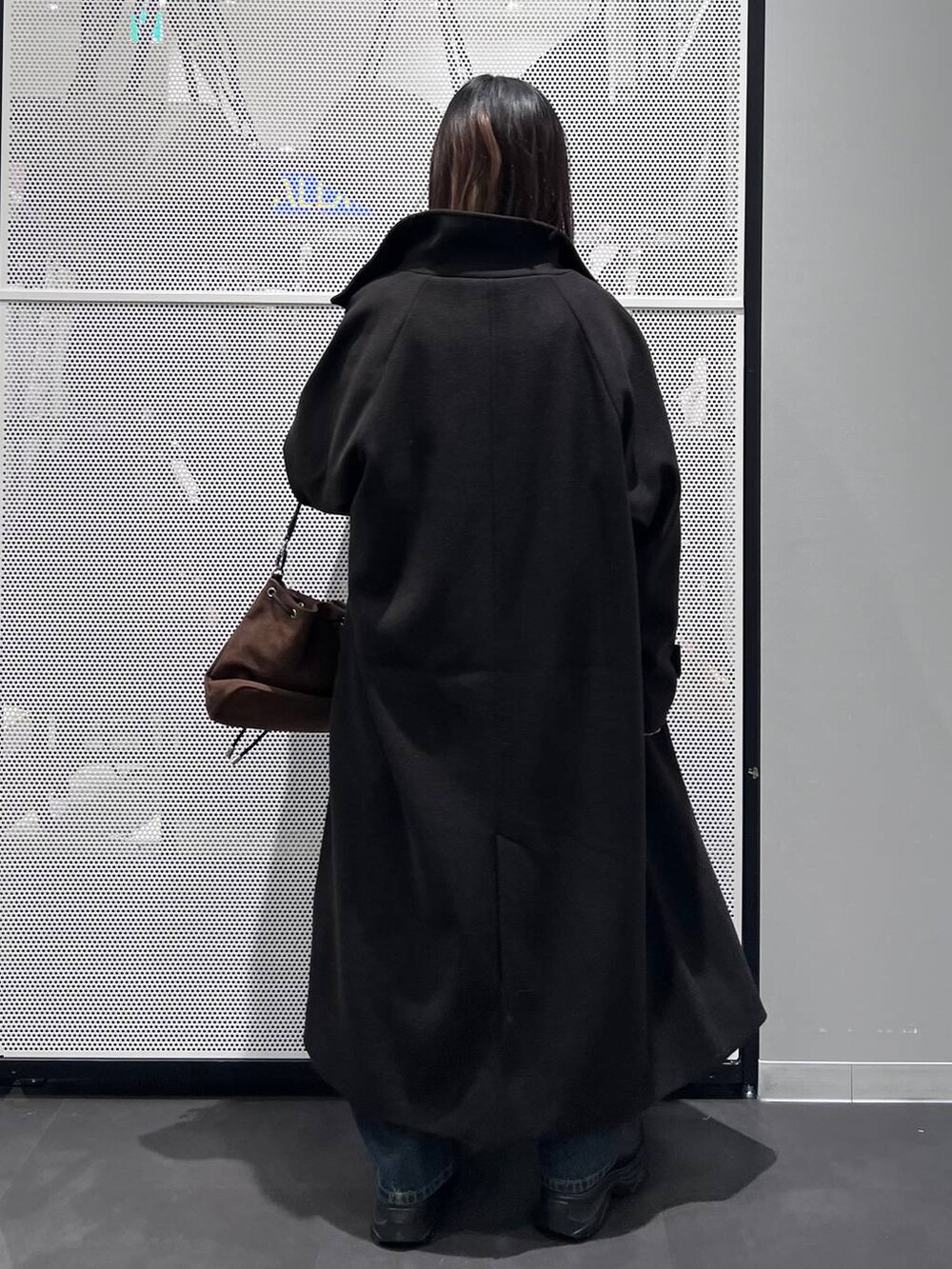 ブルー系のデニムパンツ、ブラック系のその他アウター、ブラウン系のショルダーバッグを着用したレディースの冬コーディネートの5枚目の写真