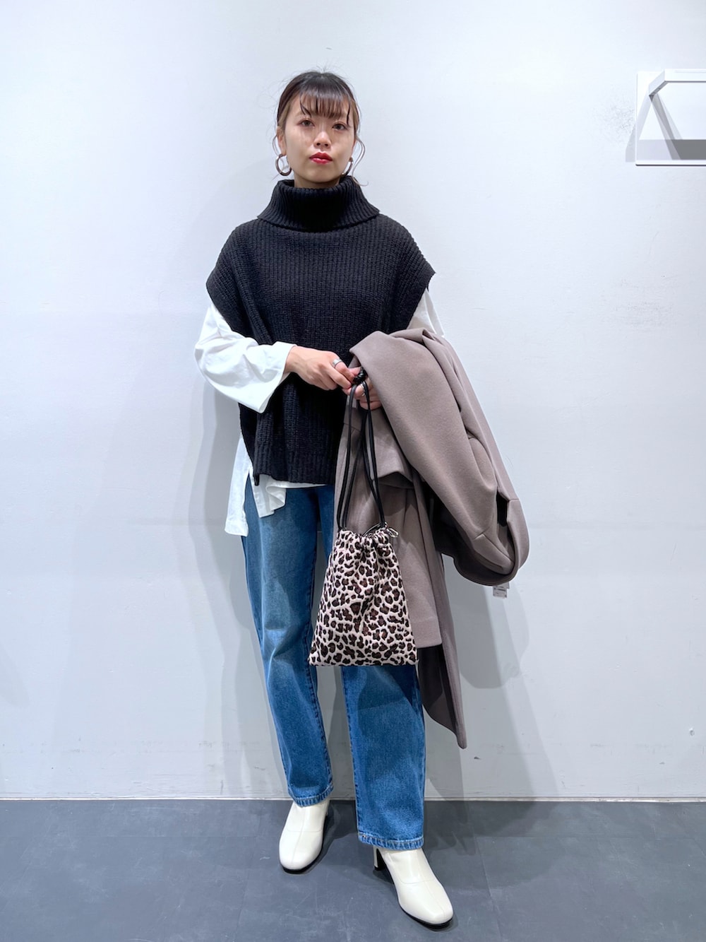 ブラック系のバッグ、ホワイト系のブーツ、ブルー系のデニムパンツを着用したレディースの冬コーディネートの2枚目の写真