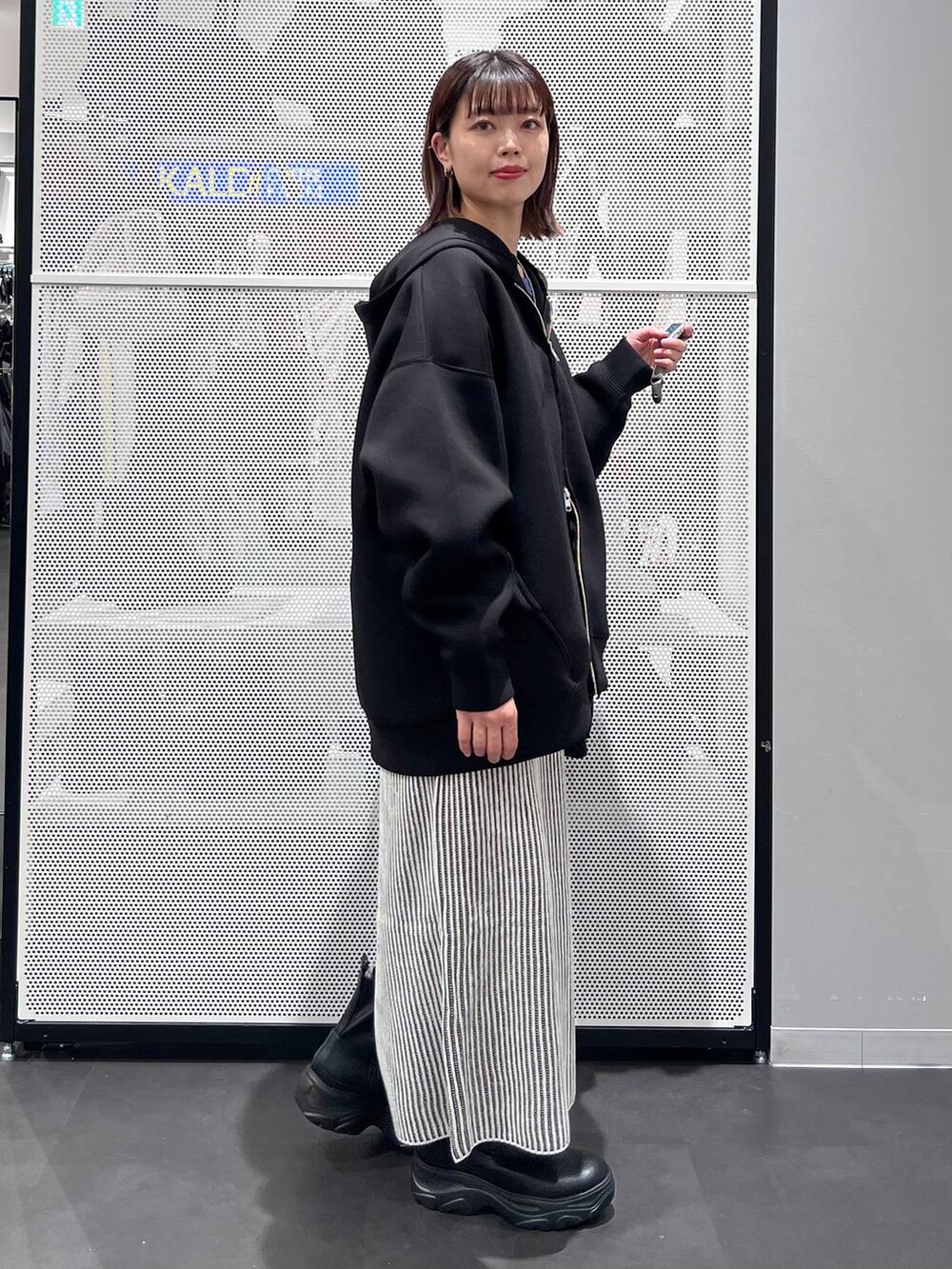 ブラック系のショルダーバッグ、ブラック系のブーツ、ブルー系のニット/セーターを着用したレディースの秋コーディネートの4枚目の写真