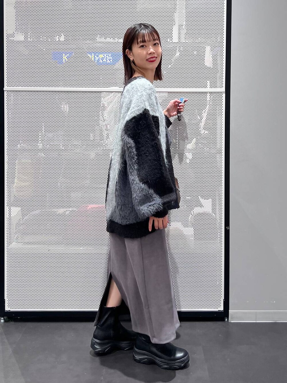 ブラウン系のショルダーバッグ、ブラック系のブーツ、グレー系のスカートを着用したレディースの秋コーディネートの4枚目の写真