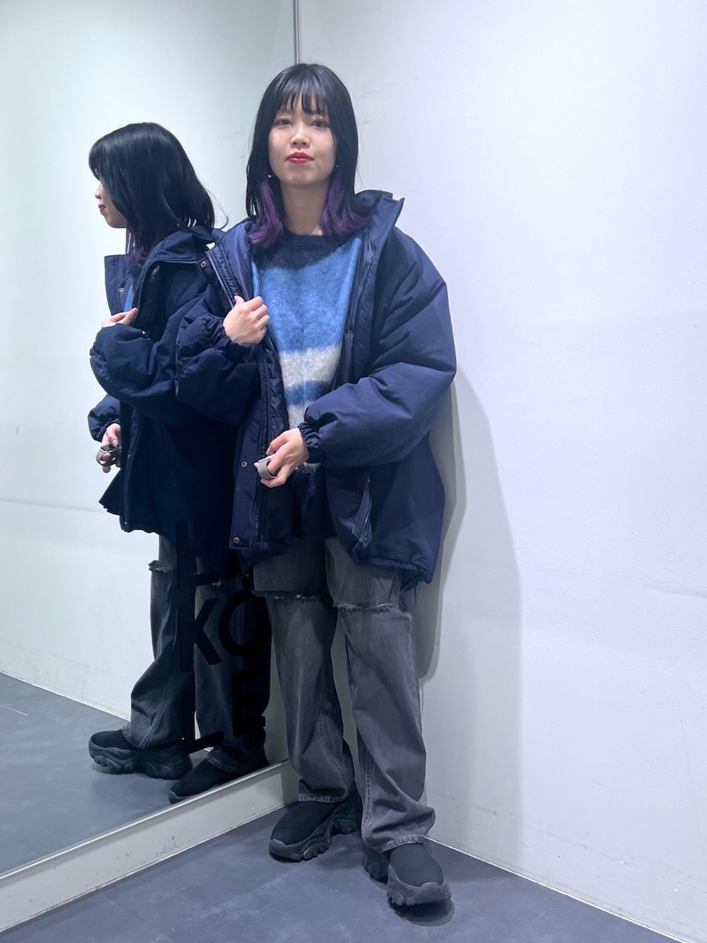 ブルー系のニット/セーター、ブルー系のナイロンジャケット、グレー系のデニムパンツを着用したレディースの冬コーディネートの2枚目の写真