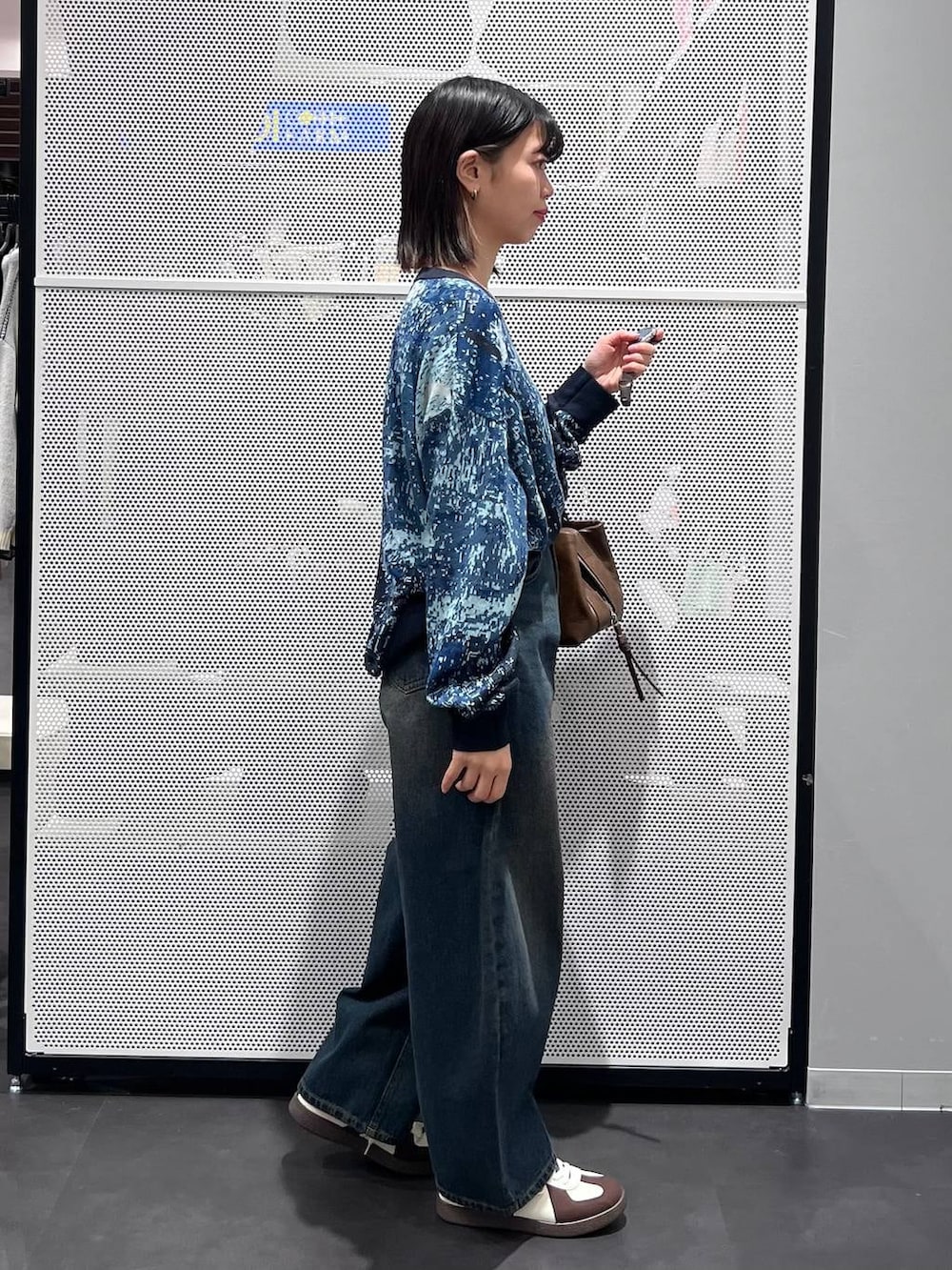 ブルー系のデニムパンツ、ホワイト系のスニーカー、ブラウン系のボストンバッグを着用したレディースの冬コーディネートの3枚目の写真