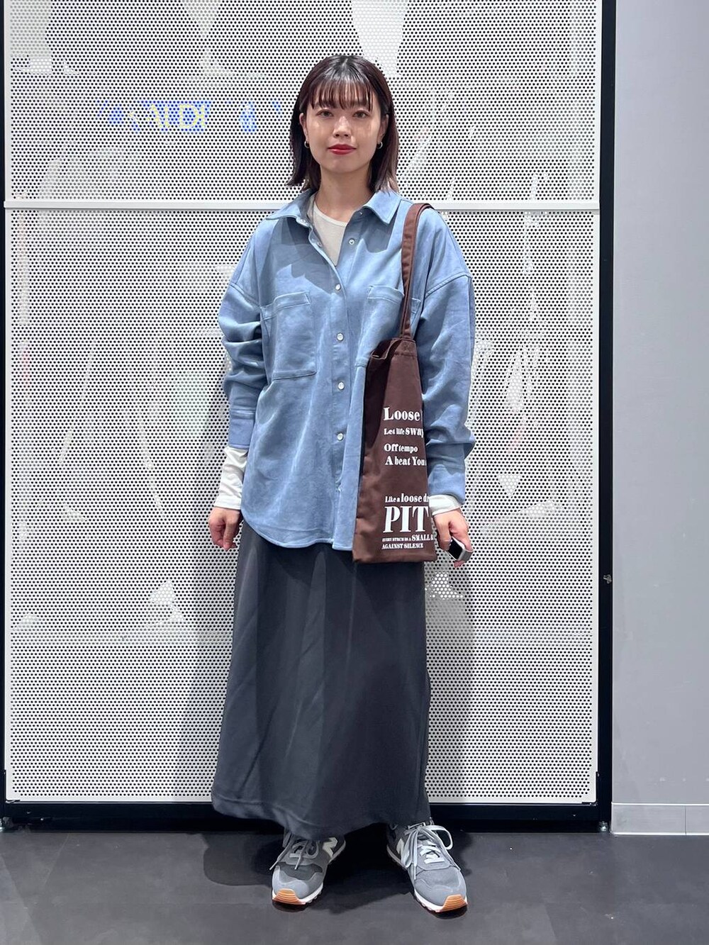 グレー系のスニーカー、ホワイト系のTシャツ/カットソー、グレー系のスカートを着用したレディースの秋コーディネートの2枚目の写真