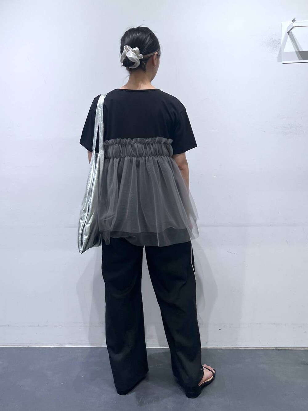 シルバー系のトートバッグ、ブラック系のサンダル、ブラック系のTシャツ/カットソーを着用したレディースの夏コーディネートの3枚目の写真