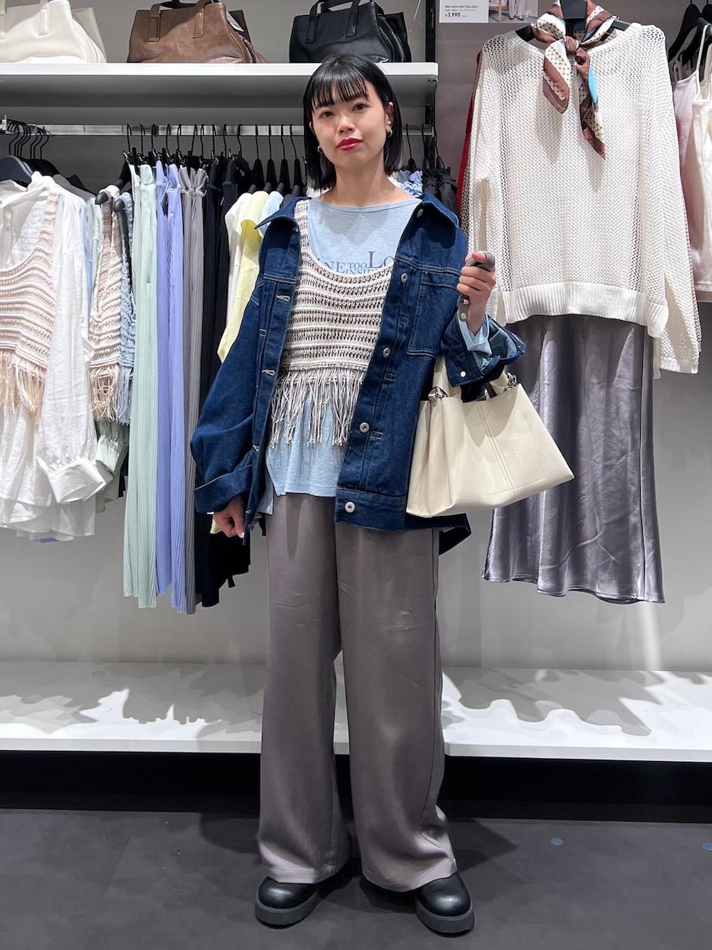 ブルー系のデニムジャケット、ブラック系のサンダル、グレー系のベストを着用したレディースの春コーディネートの2枚目の写真