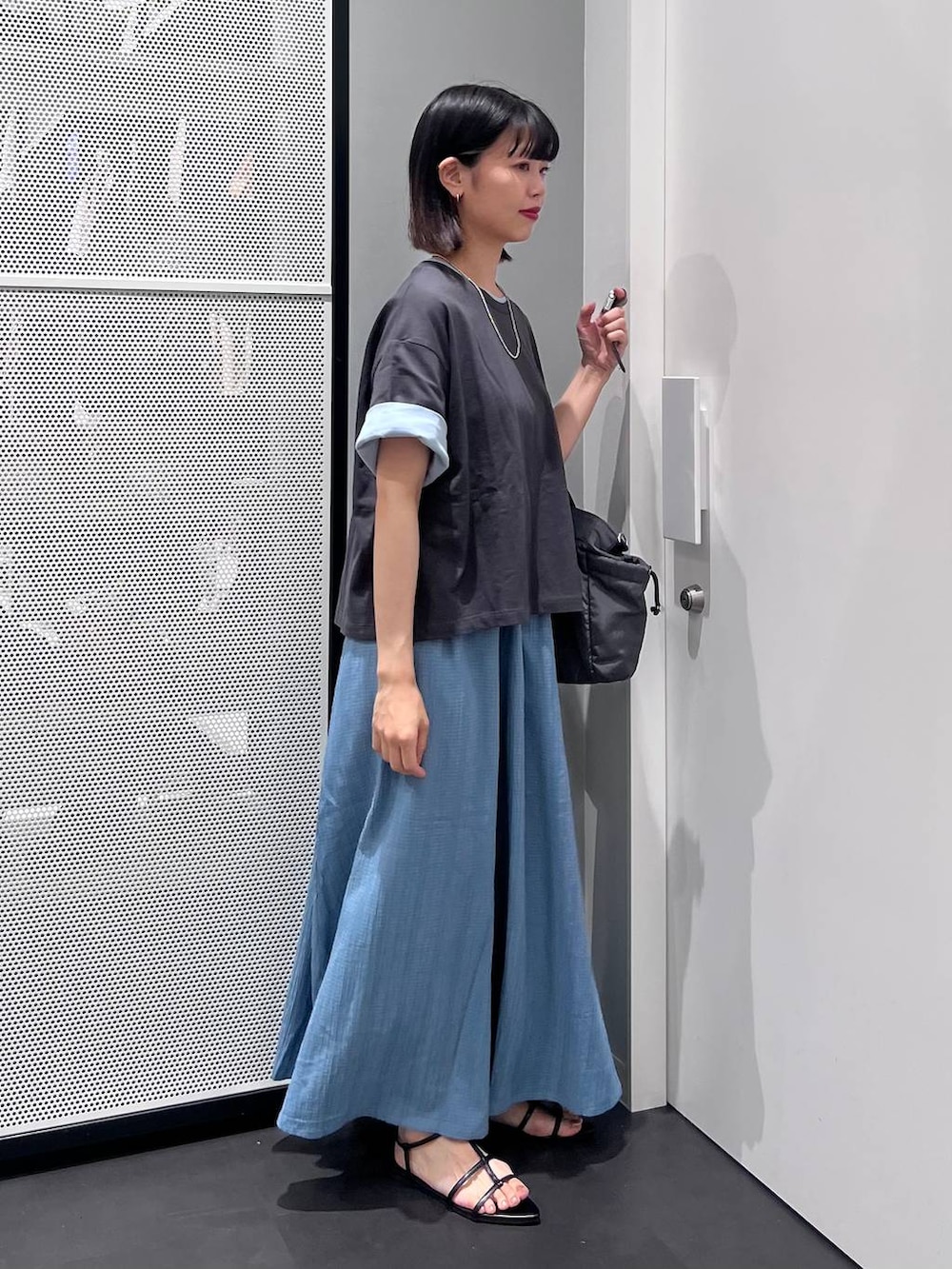 グレー系のTシャツ/カットソー、グレー系のトートバッグ、ブラック系のサンダルを着用したレディースの夏コーディネートの3枚目の写真