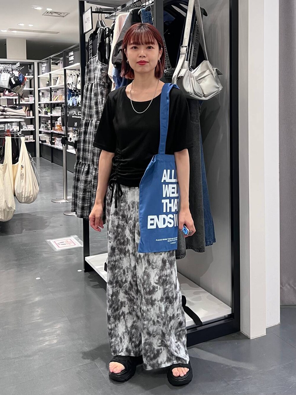 ブラック系のスニーカー、ブラック系のTシャツ/カットソー、ブルー系のトートバッグを着用したレディースの夏コーディネートの2枚目の写真