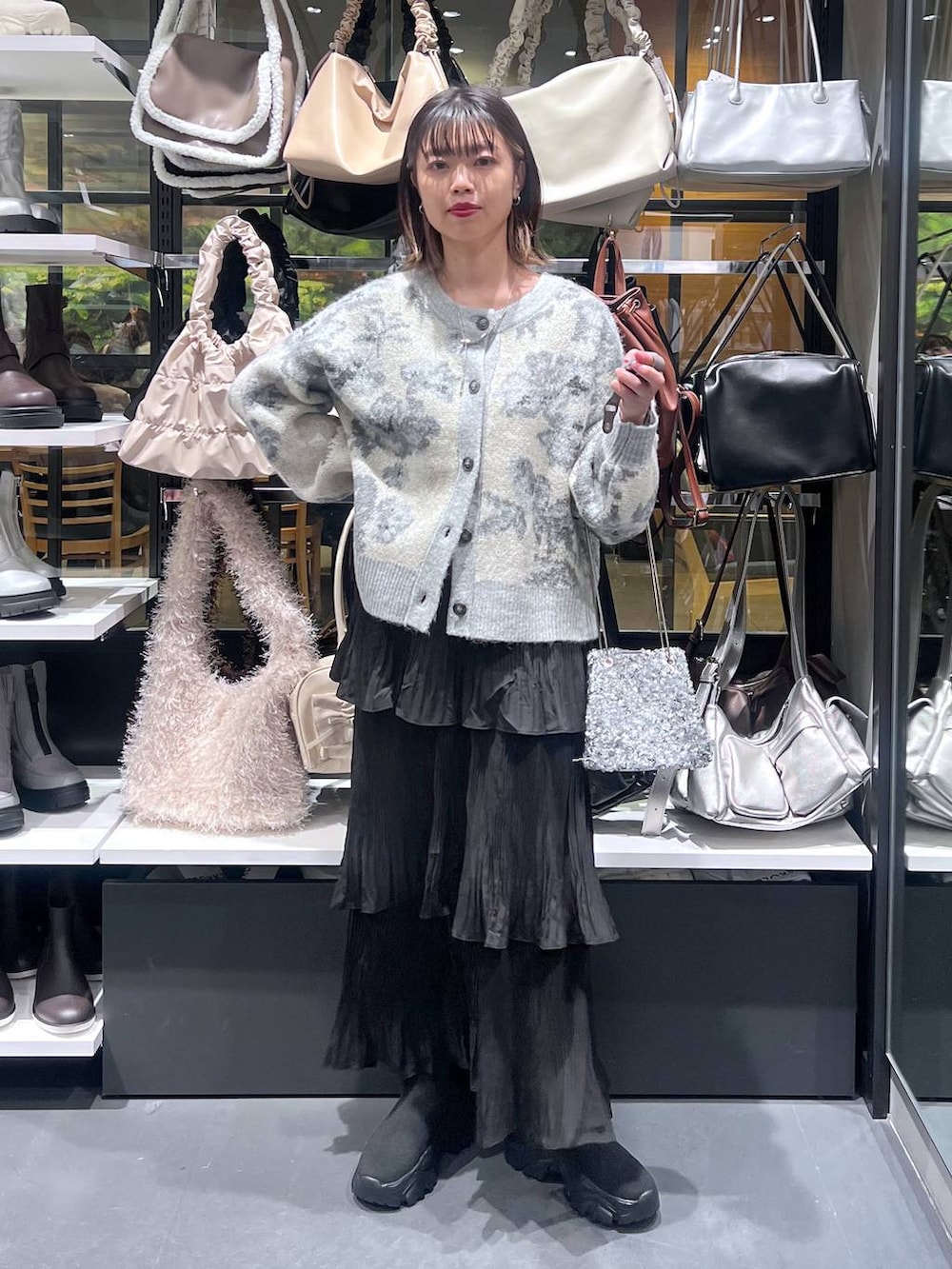 ブラック系のスカート、ブラック系のブーツ、ホワイト系のカーディガン/ボレロを着用したレディースの秋コーディネートの2枚目の写真