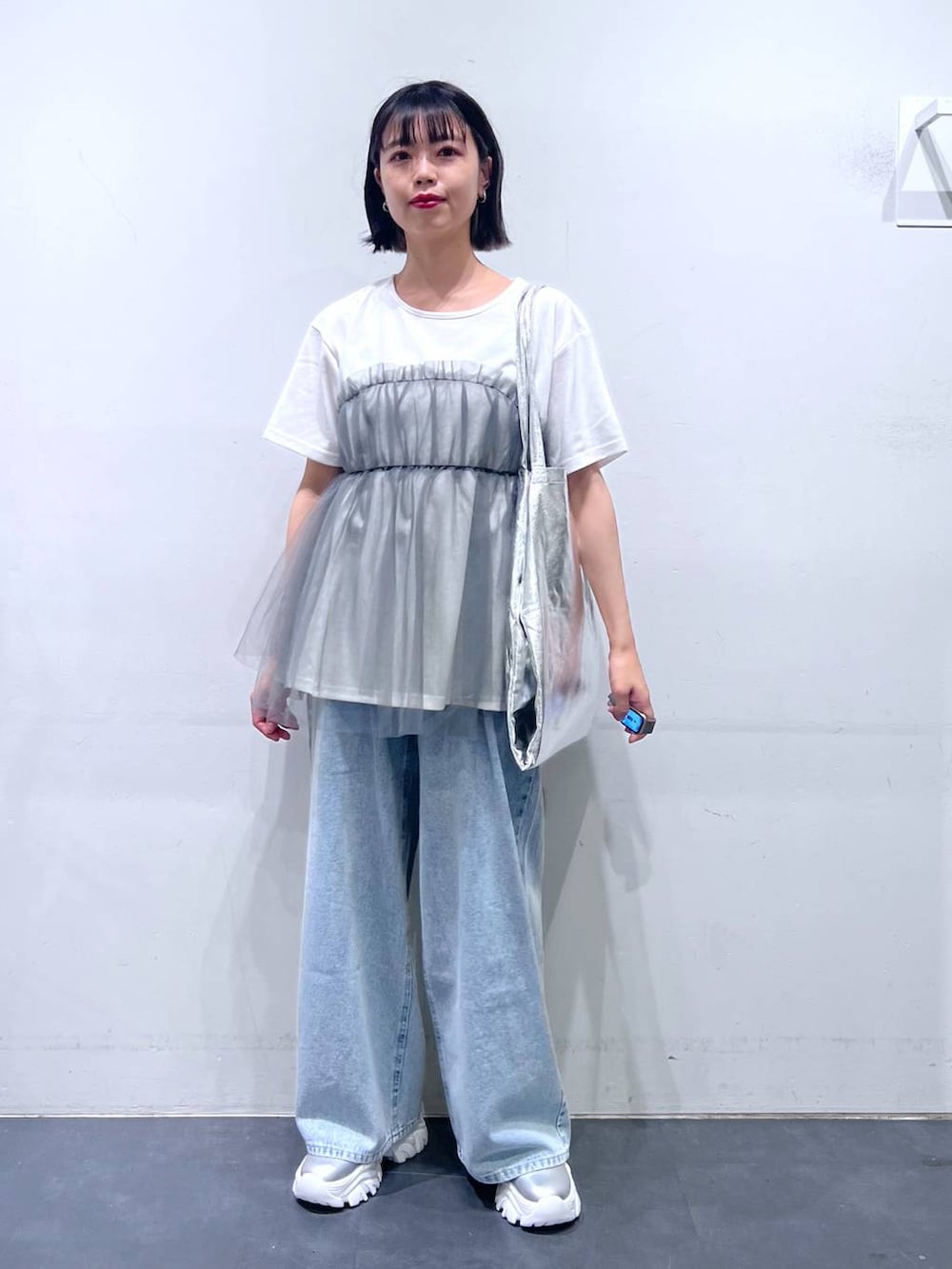 シルバー系のトートバッグ、ブルー系のデニムパンツ、グレー系のTシャツ/カットソーを着用したレディースの夏コーディネートの2枚目の写真