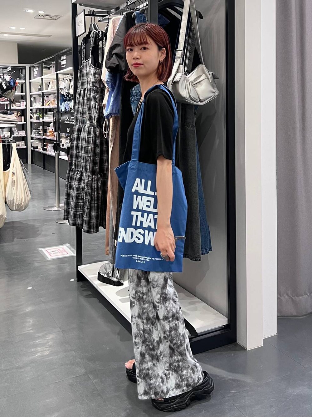 ブラック系のスニーカー、ブラック系のTシャツ/カットソー、ブルー系のトートバッグを着用したレディースの夏コーディネートの3枚目の写真