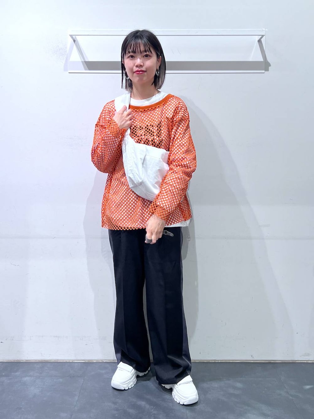 ホワイト系のスニーカー、ホワイト系のショルダーバッグ、オレンジ系のTシャツ/カットソーを着用したレディースの春コーディネートの2枚目の写真