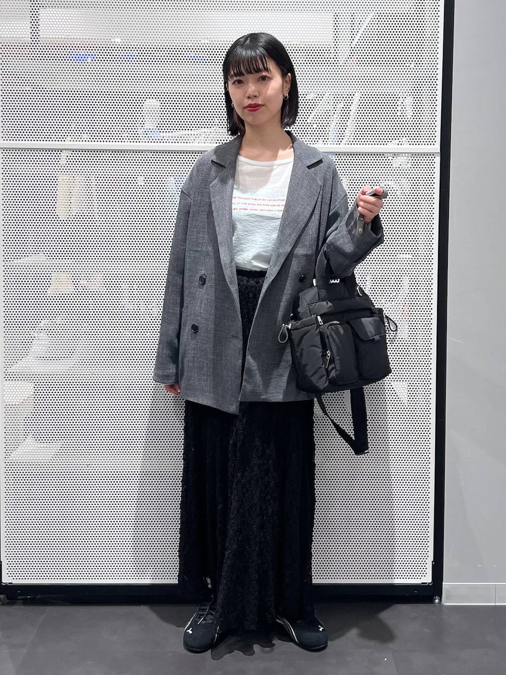 ブラック系のスニーカー、ブラック系のトートバッグ、ブラック系のスカートを着用したレディースの春コーディネートの2枚目の写真