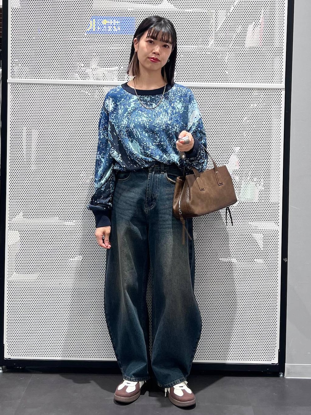 ブルー系のデニムパンツ、ホワイト系のスニーカー、ブラウン系のボストンバッグを着用したレディースの冬コーディネートの2枚目の写真