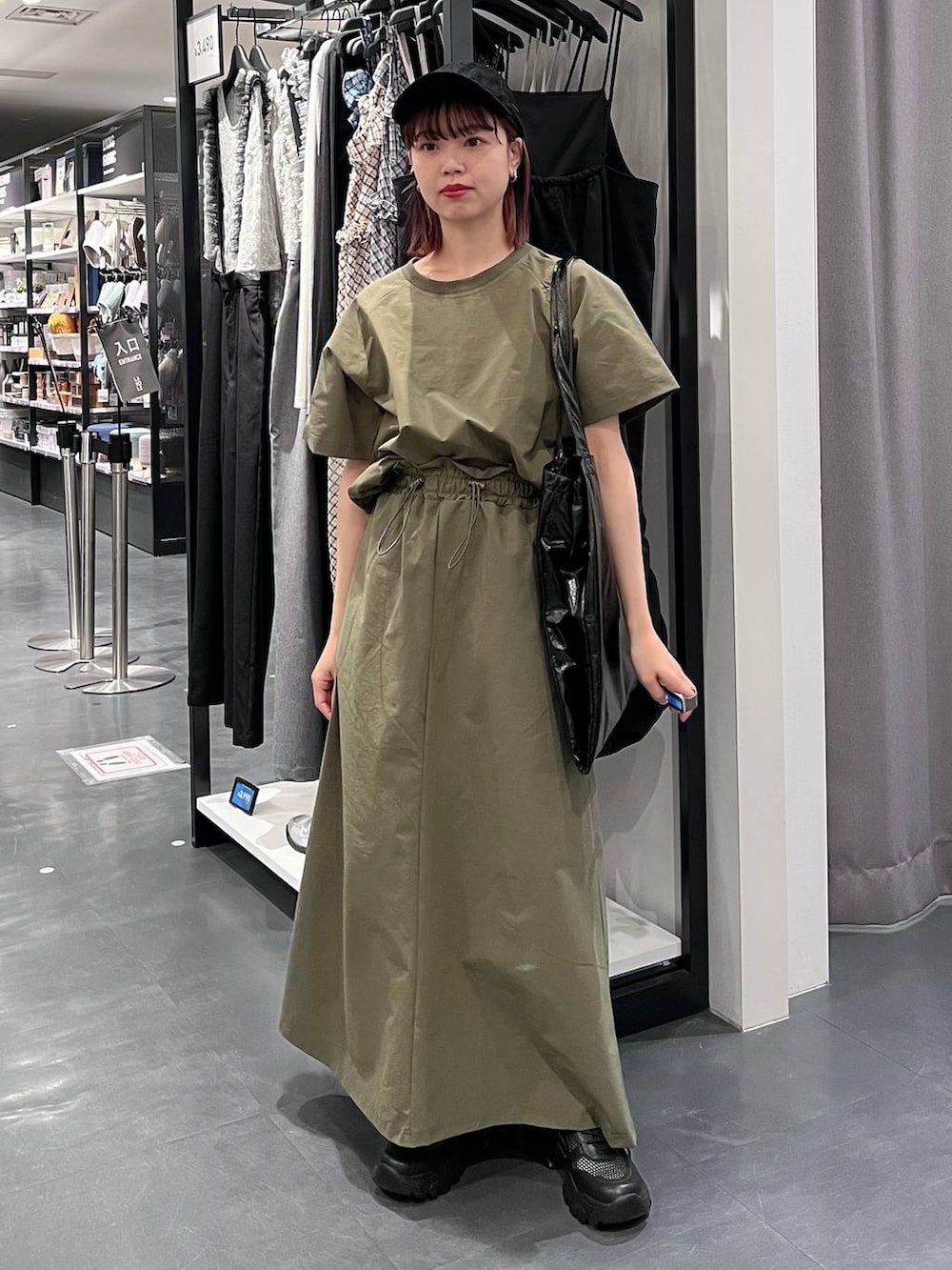 ブラック系のトートバッグ、ブラック系のスニーカー、グリーン系のTシャツ/カットソーを着用したレディースの春コーディネートの2枚目の写真