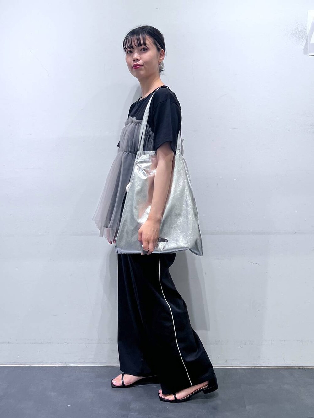 シルバー系のトートバッグ、ブラック系のサンダル、ブラック系のTシャツ/カットソーを着用したレディースの夏コーディネートの2枚目の写真