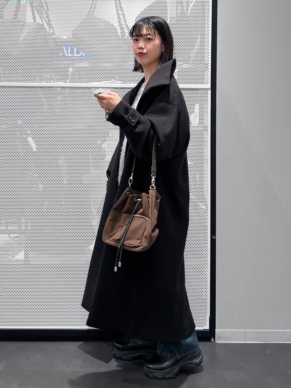 ブルー系のデニムパンツ、ブラック系のその他アウター、ブラウン系のショルダーバッグを着用したレディースの冬コーディネートの3枚目の写真