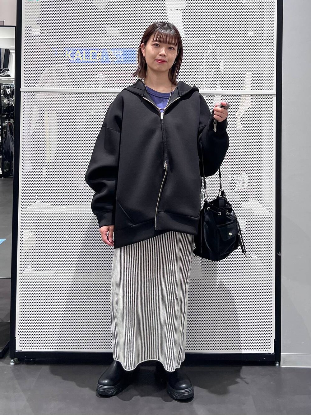 ブラック系のショルダーバッグ、ブラック系のブーツ、ブルー系のニット/セーターを着用したレディースの秋コーディネートの2枚目の写真