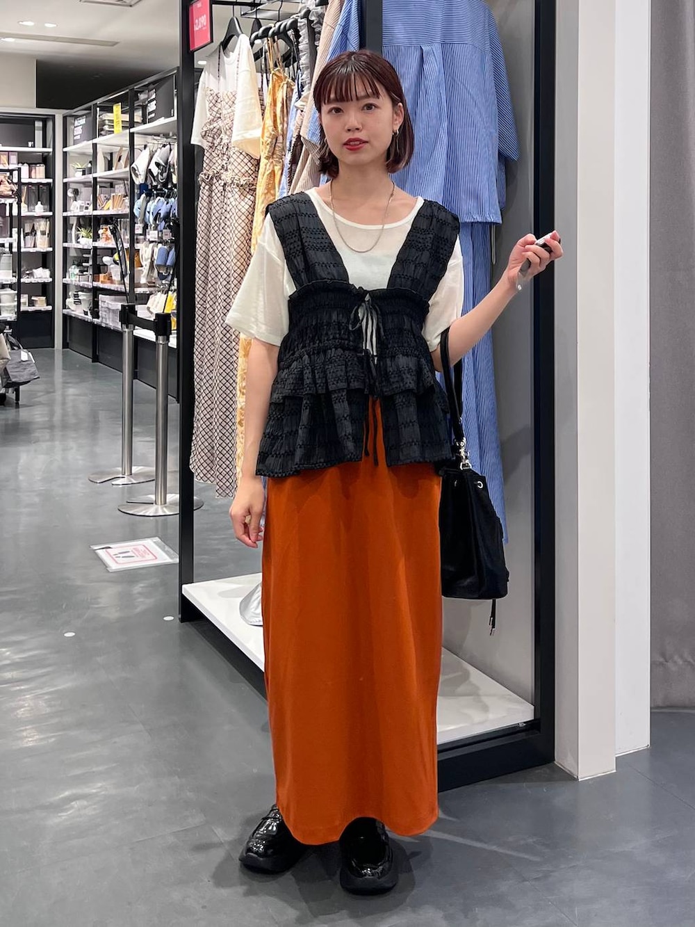 ホワイト系のTシャツ/カットソー、オレンジ系のスカート、ブラック系のローファーを着用したレディースの夏コーディネートの3枚目の写真