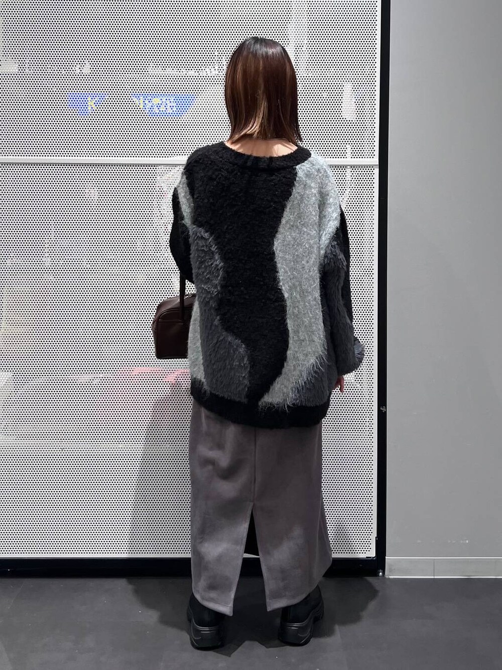 ブラウン系のショルダーバッグ、ブラック系のブーツ、グレー系のスカートを着用したレディースの秋コーディネートの5枚目の写真