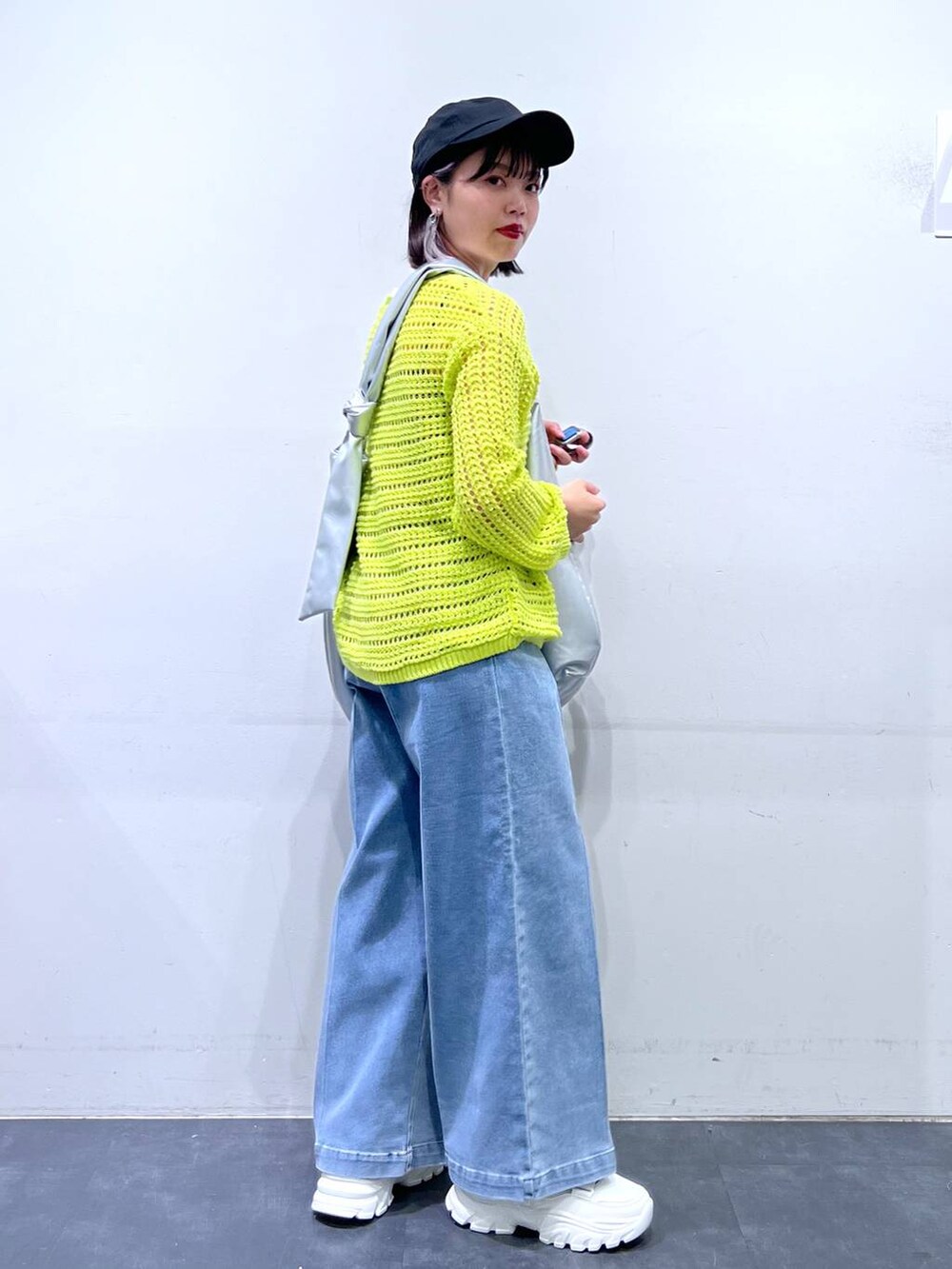 ホワイト系のスニーカー、ブルー系のデニムパンツ、ホワイト系のキャミソールを着用したレディースの春コーディネートの4枚目の写真