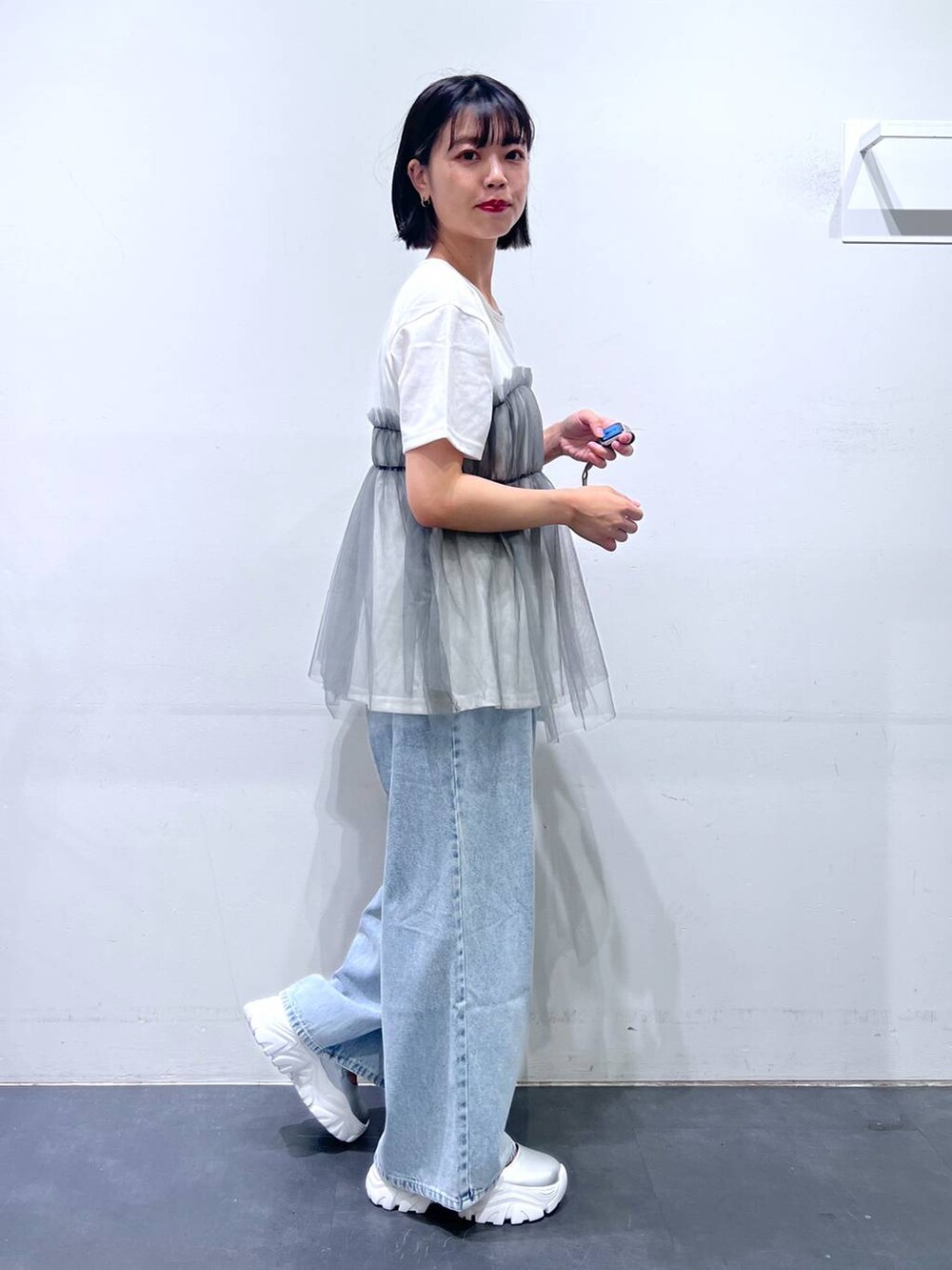 シルバー系のトートバッグ、ブルー系のデニムパンツ、グレー系のTシャツ/カットソーを着用したレディースの夏コーディネートの4枚目の写真