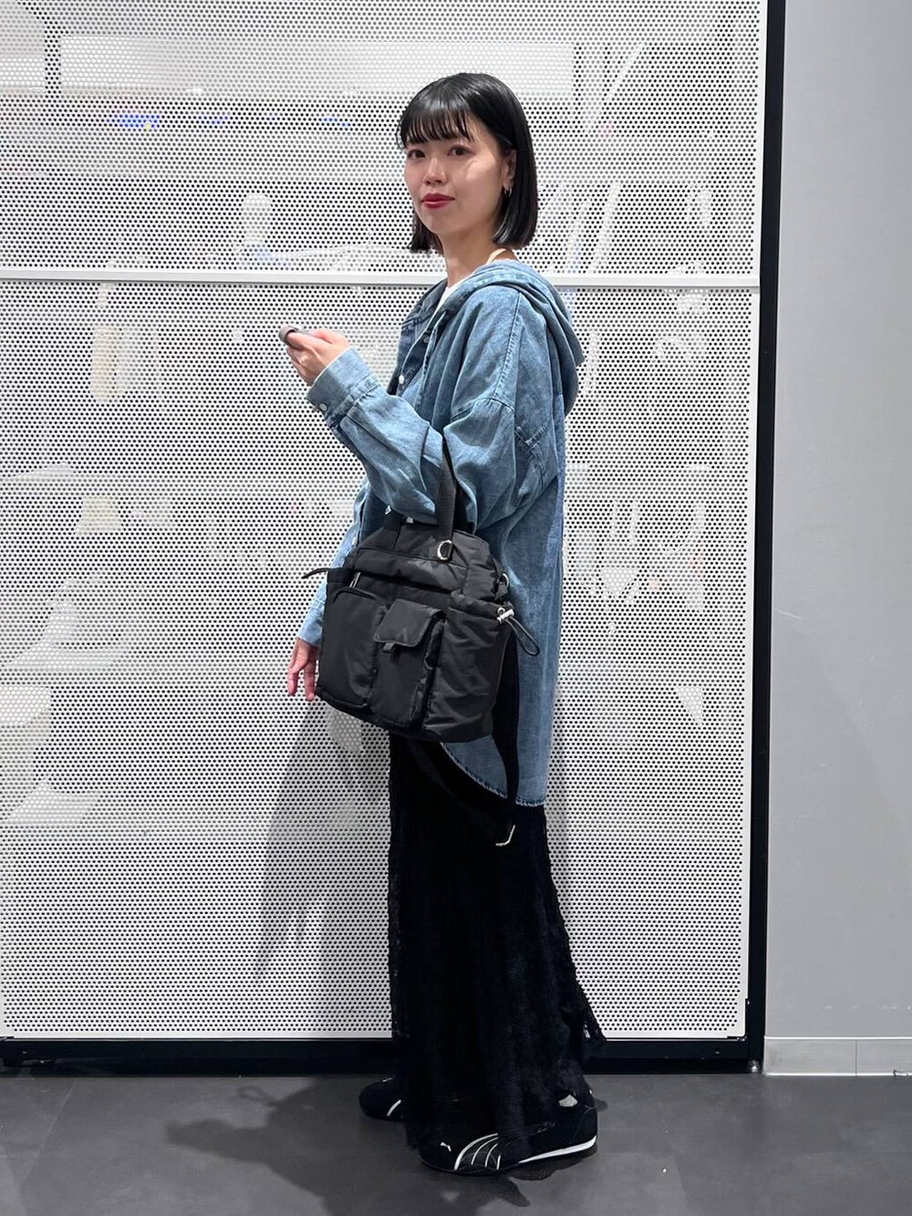 ブラック系のスニーカー、ブラック系のトートバッグ、ブラック系のスカートを着用したレディースの春コーディネートの2枚目の写真