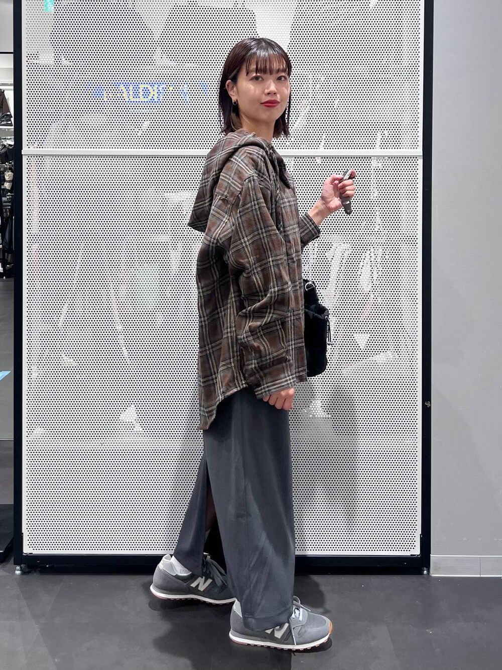 グレー系のスニーカー、グレー系のスカート、ホワイト系のTシャツ/カットソーを着用したレディースの秋コーディネートの4枚目の写真