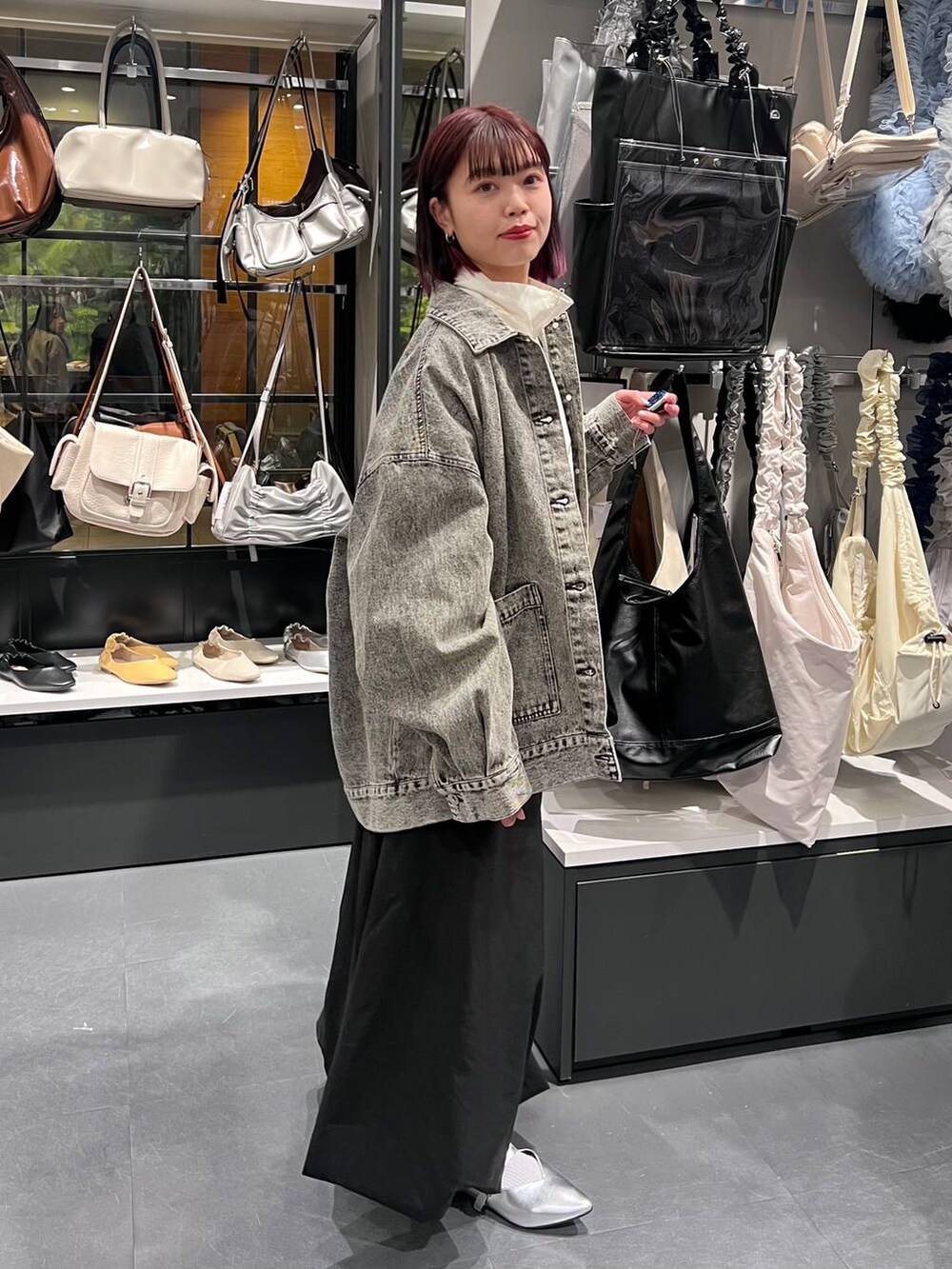 ブラック系のトートバッグ、シルバー系のパンプス、ブラック系のデニムジャケットを着用したレディースの春コーディネートの3枚目の写真