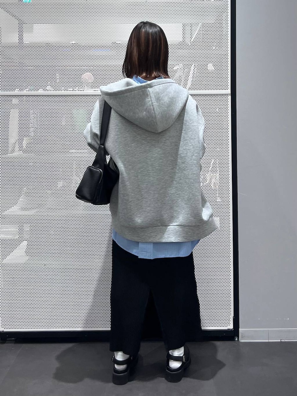 グレー系のパーカー、ブラック系のショルダーバッグ、ブラック系のサンダルを着用したレディースの春コーディネートの4枚目の写真