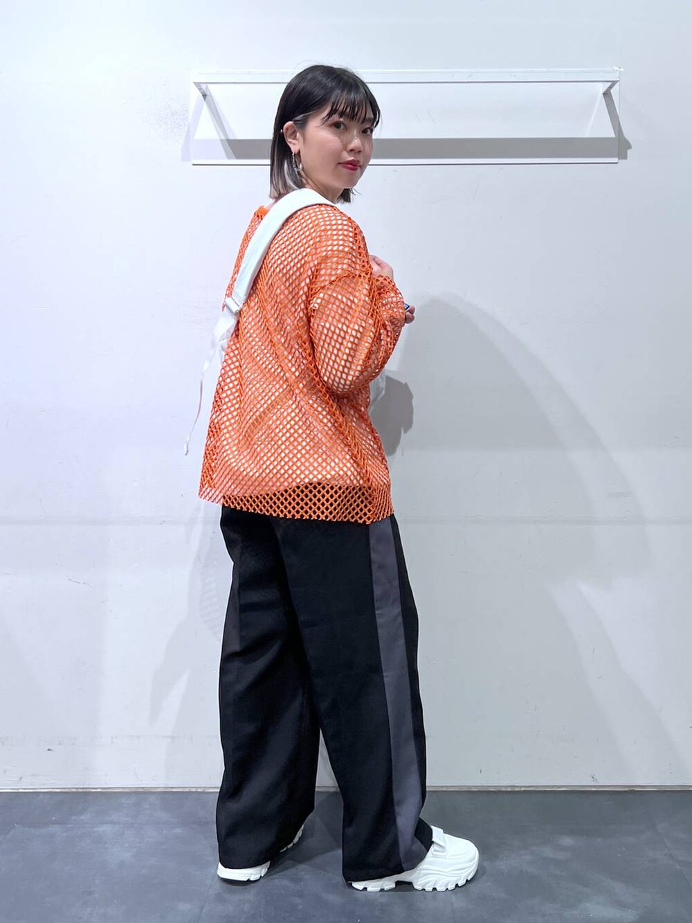 ホワイト系のスニーカー、ホワイト系のショルダーバッグ、オレンジ系のTシャツ/カットソーを着用したレディースの春コーディネートの4枚目の写真