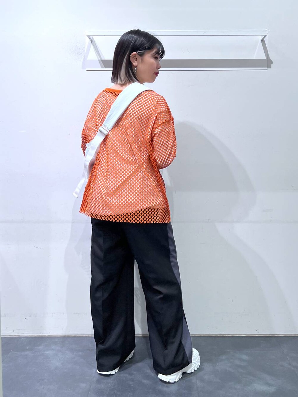 ホワイト系のスニーカー、ホワイト系のショルダーバッグ、オレンジ系のTシャツ/カットソーを着用したレディースの春コーディネートの5枚目の写真