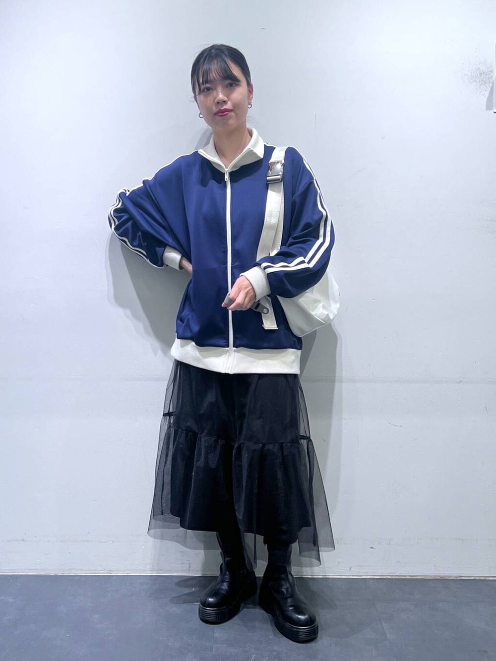 ブラック系のブーツ、ホワイト系のショルダーバッグ、ブルー系のスウェットを着用したレディースの冬コーディネートの2枚目の写真