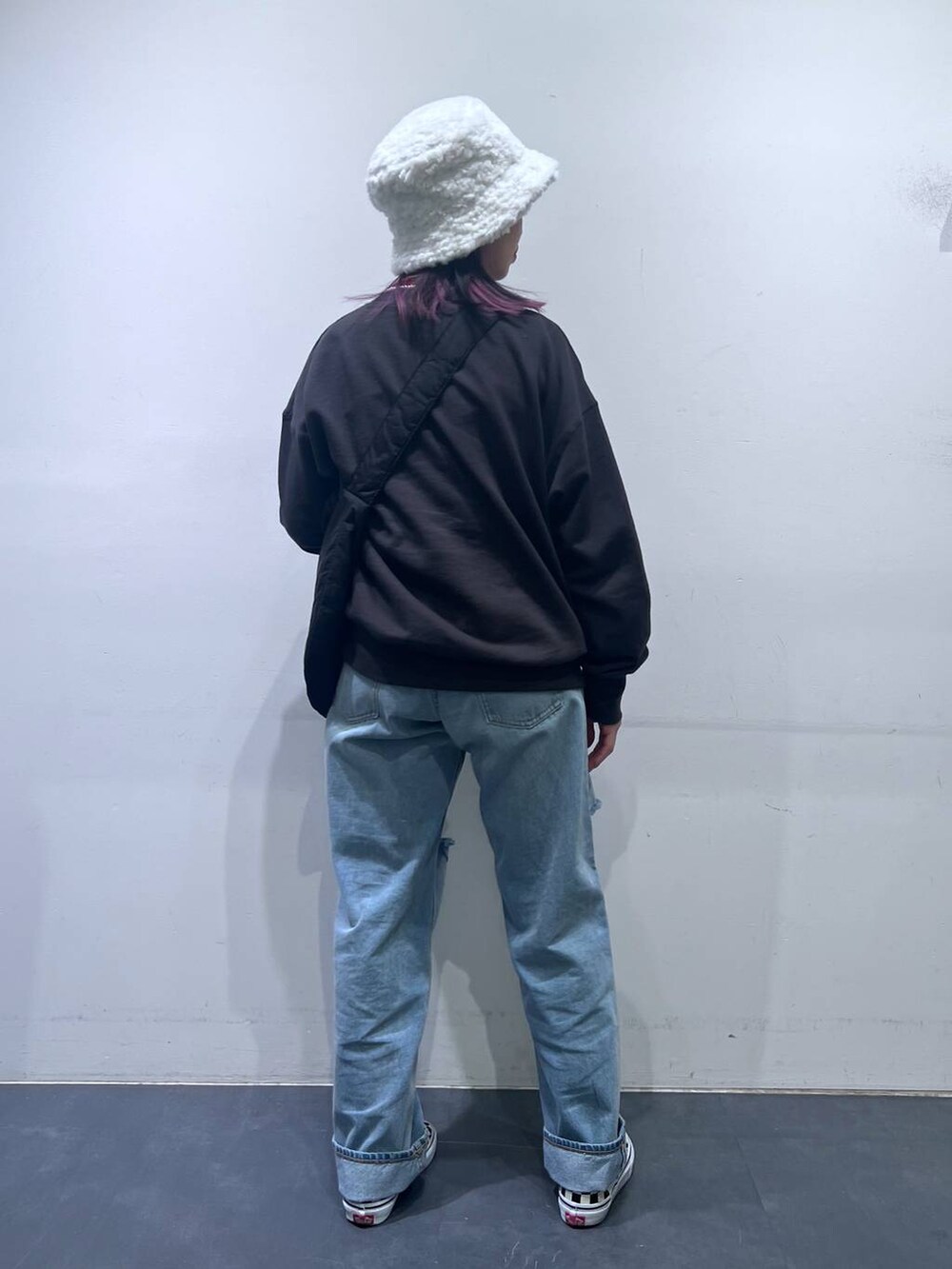 ブラック系のショルダーバッグ、ブルー系のデニムパンツ、ホワイト系のハットを着用したレディースの冬コーディネートの4枚目の写真