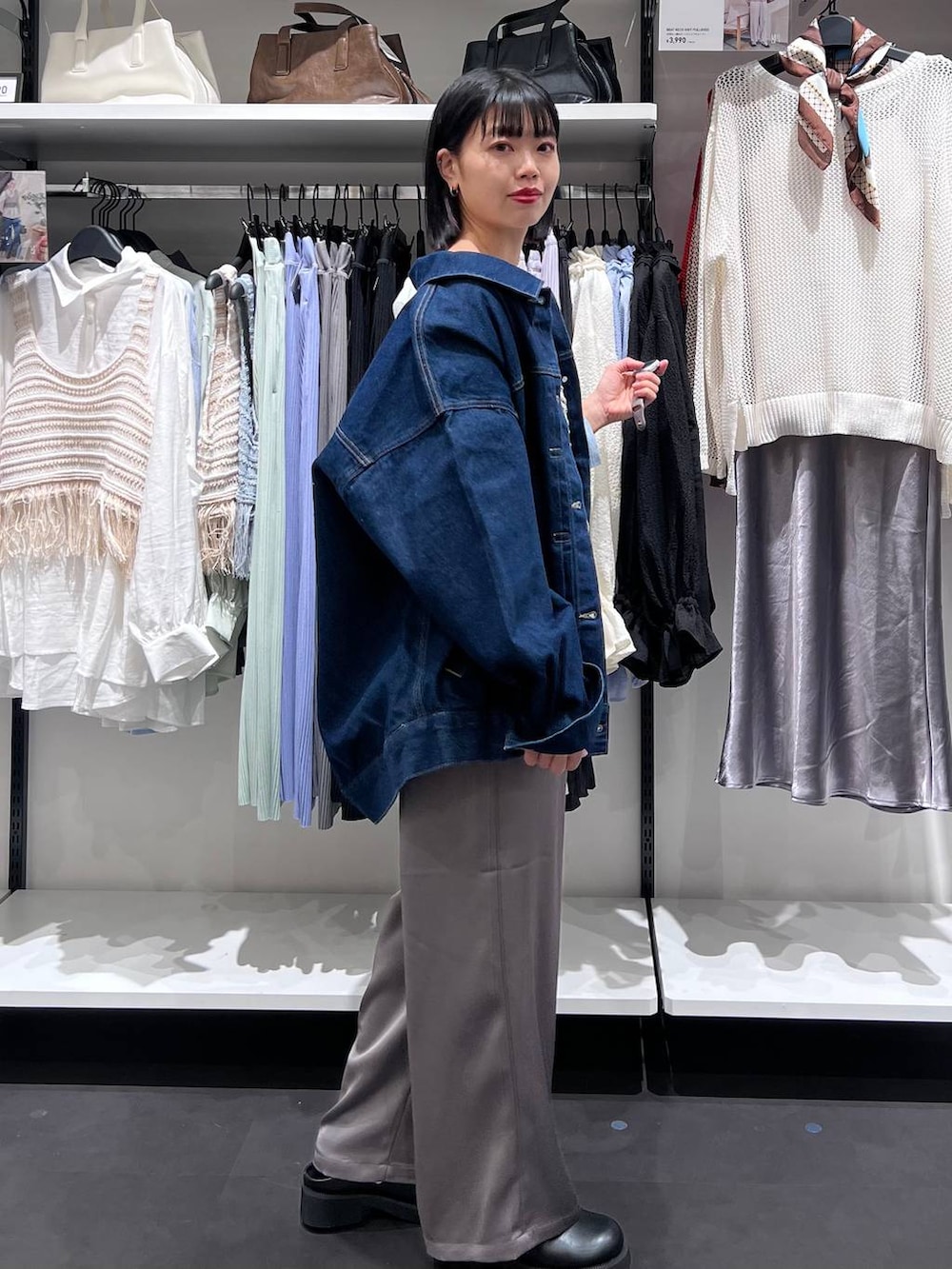 ブルー系のデニムジャケット、ブラック系のサンダル、グレー系のベストを着用したレディースの春コーディネートの3枚目の写真