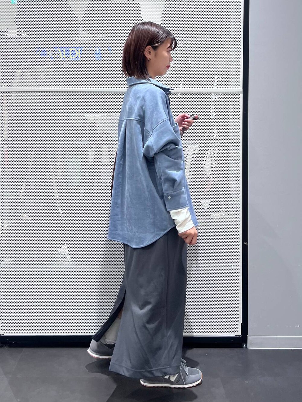 グレー系のスニーカー、ホワイト系のTシャツ/カットソー、グレー系のスカートを着用したレディースの秋コーディネートの3枚目の写真