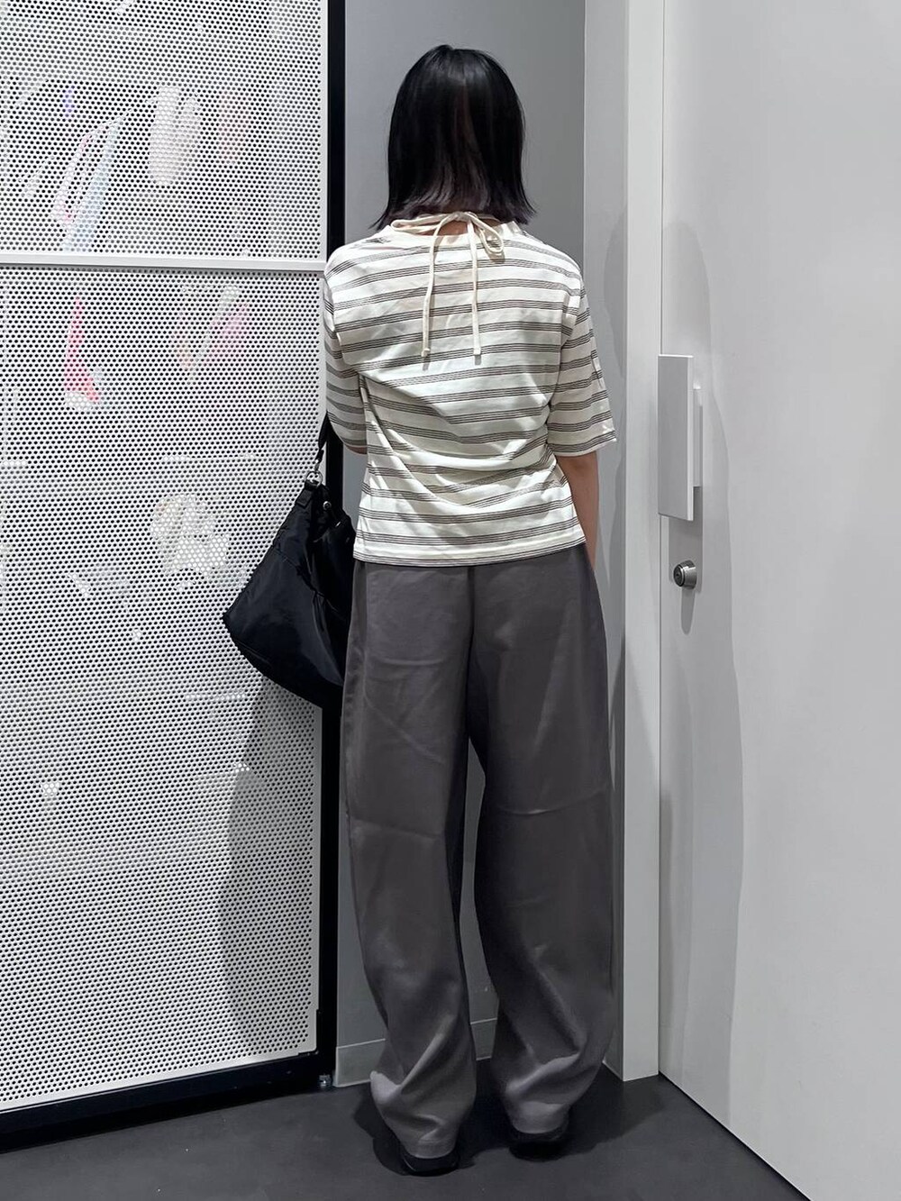 ブラック系のハンドバッグ、グレー系のスラックス、ベージュ系のTシャツ/カットソーを着用したレディースの夏コーディネートの5枚目の写真
