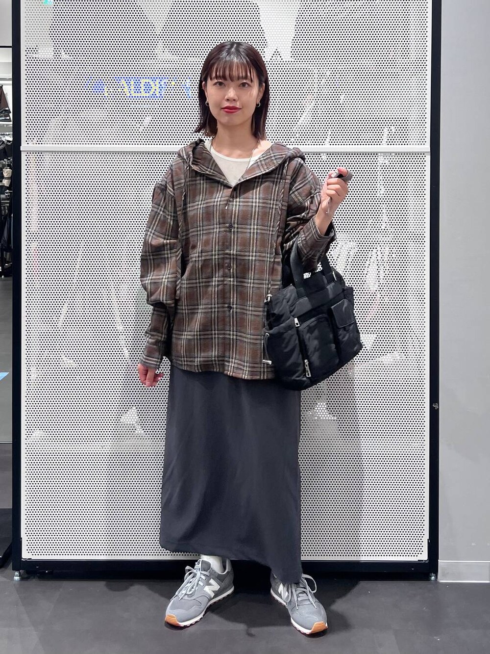 グレー系のスニーカー、グレー系のスカート、ホワイト系のTシャツ/カットソーを着用したレディースの秋コーディネートの2枚目の写真