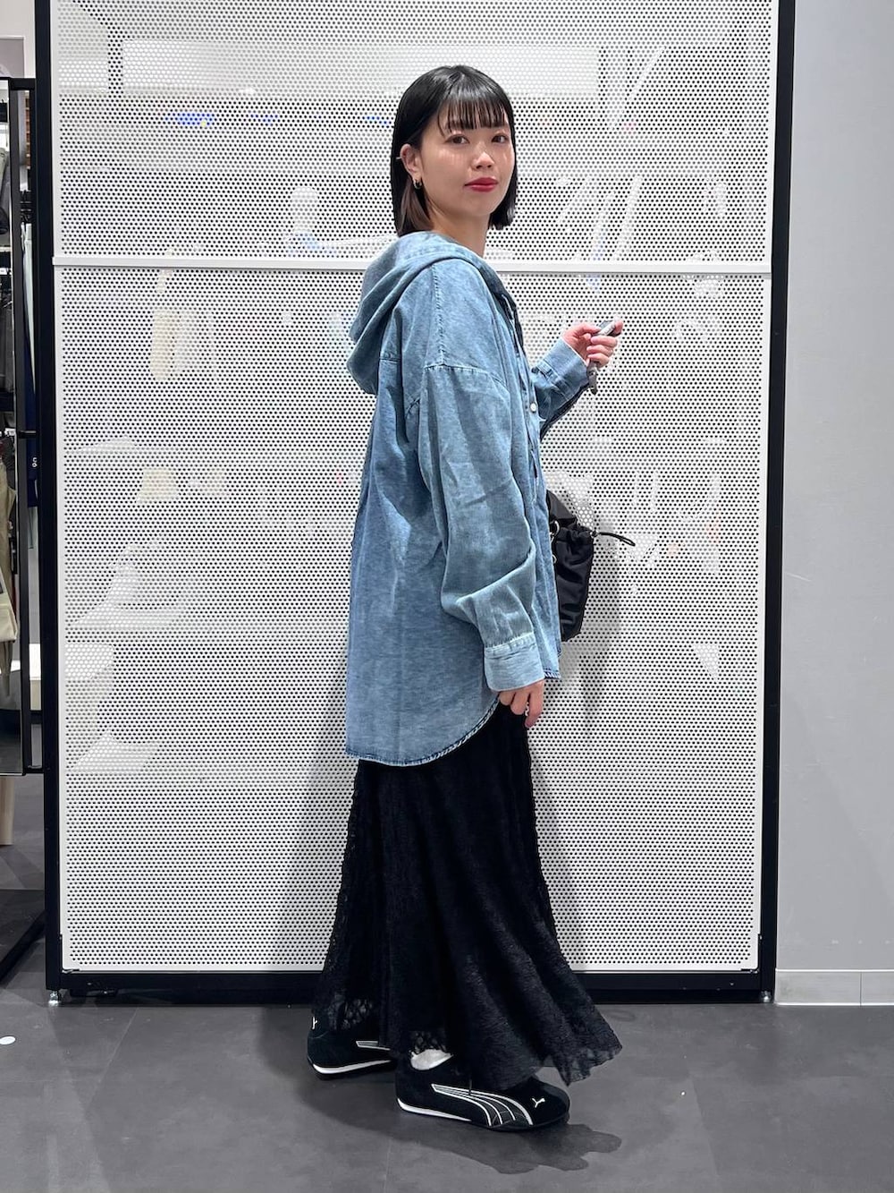 ブラック系のスニーカー、ブラック系のトートバッグ、ブラック系のスカートを着用したレディースの春コーディネートの3枚目の写真