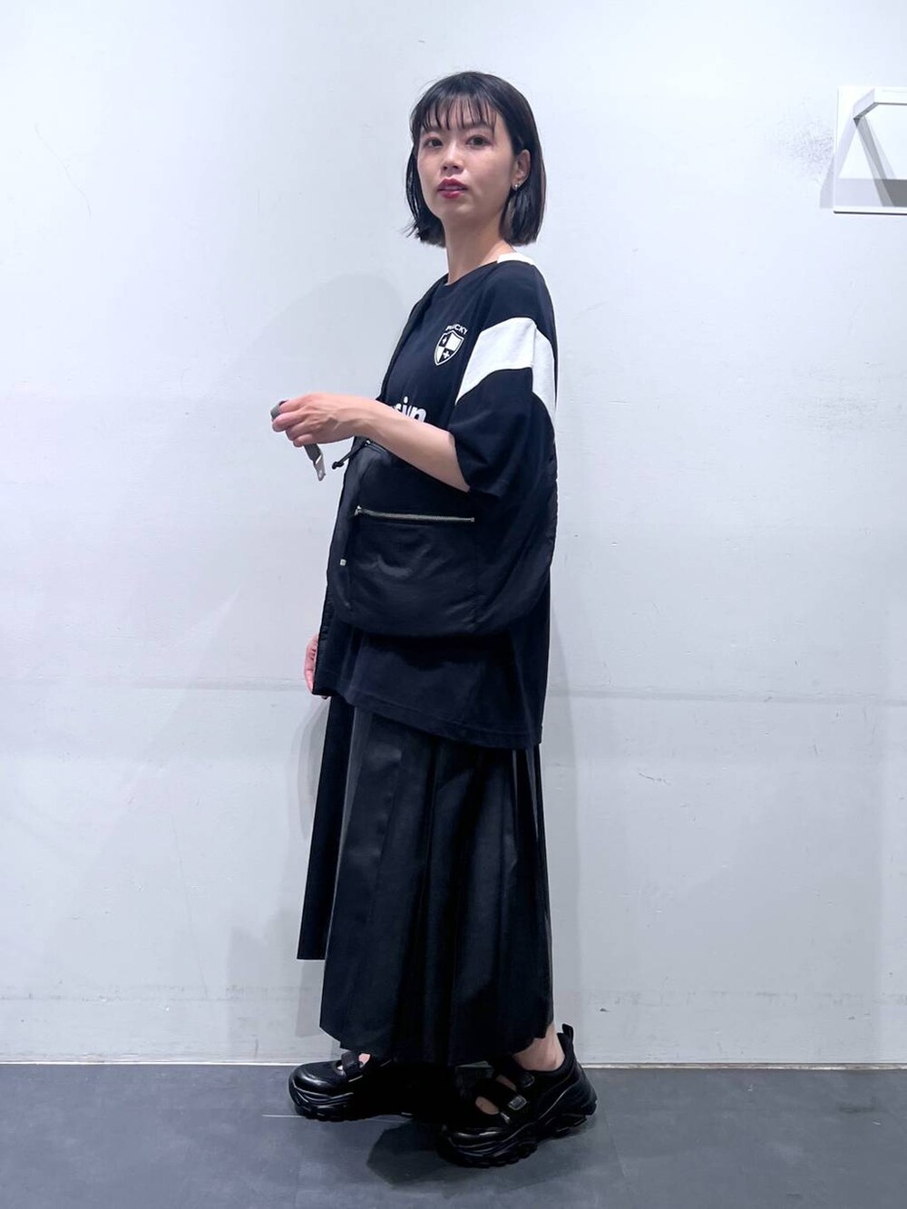 ブラック系のショルダーバッグ、ブラック系のTシャツ/カットソー、ブラック系のスニーカーを着用したレディースの夏コーディネートの3枚目の写真