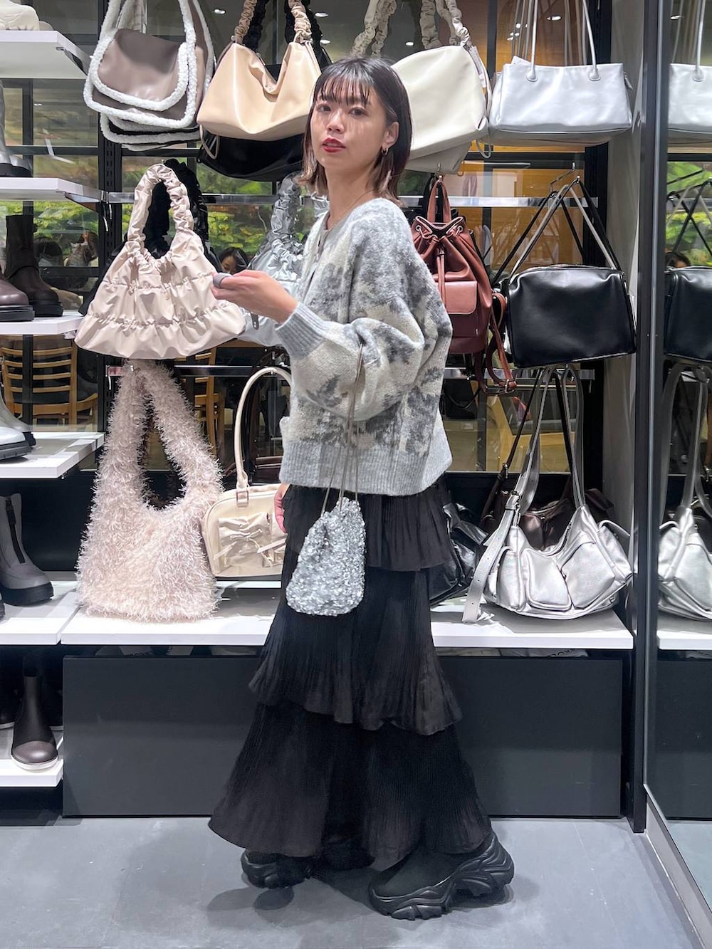 ブラック系のスカート、ブラック系のブーツ、ホワイト系のカーディガン/ボレロを着用したレディースの秋コーディネートの3枚目の写真