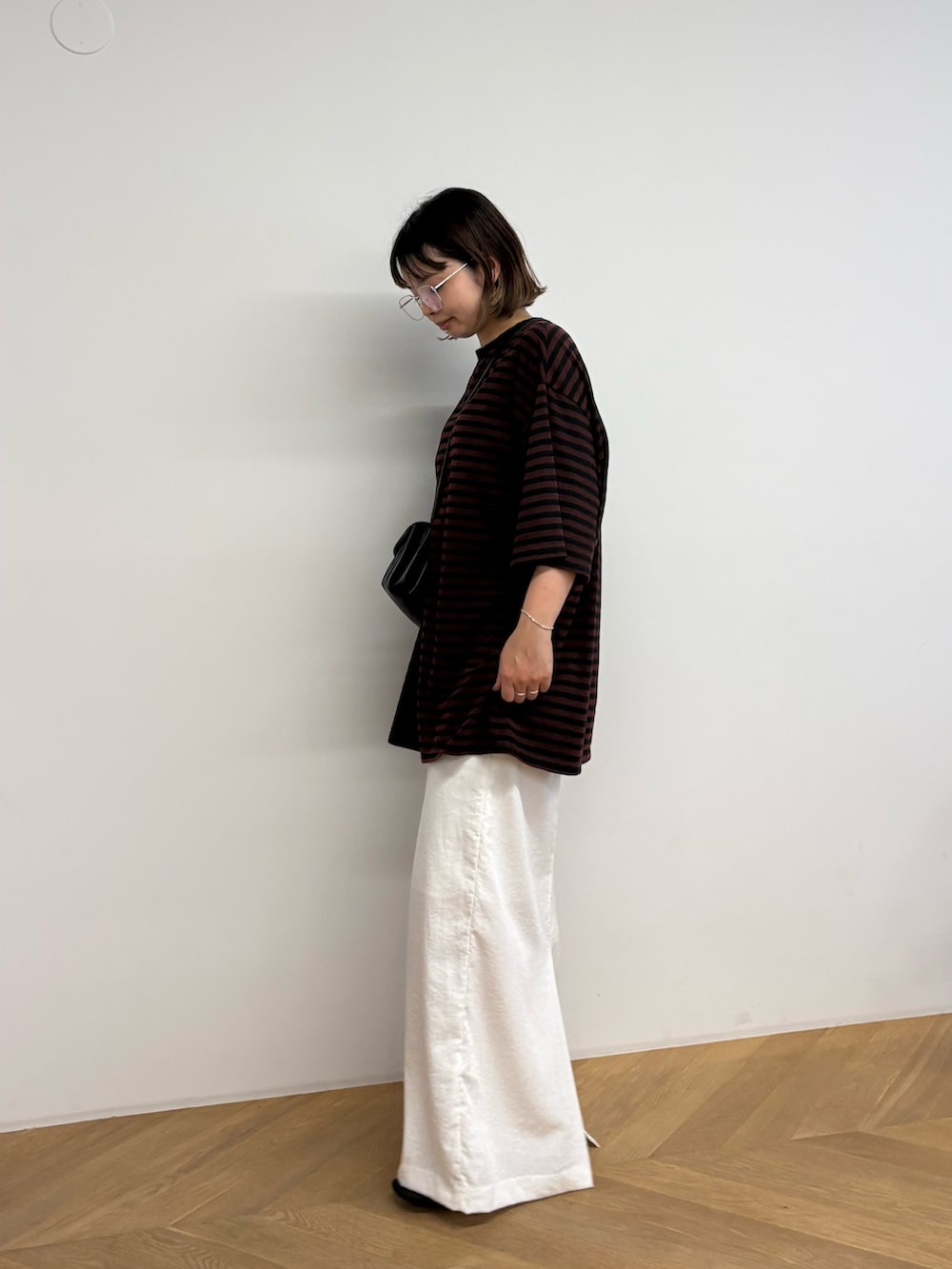 ブラウン系のTシャツ/カットソー、ブラック系のショルダーバッグ、ホワイト系のスカートを着用したレディースの夏コーディネートの2枚目の写真