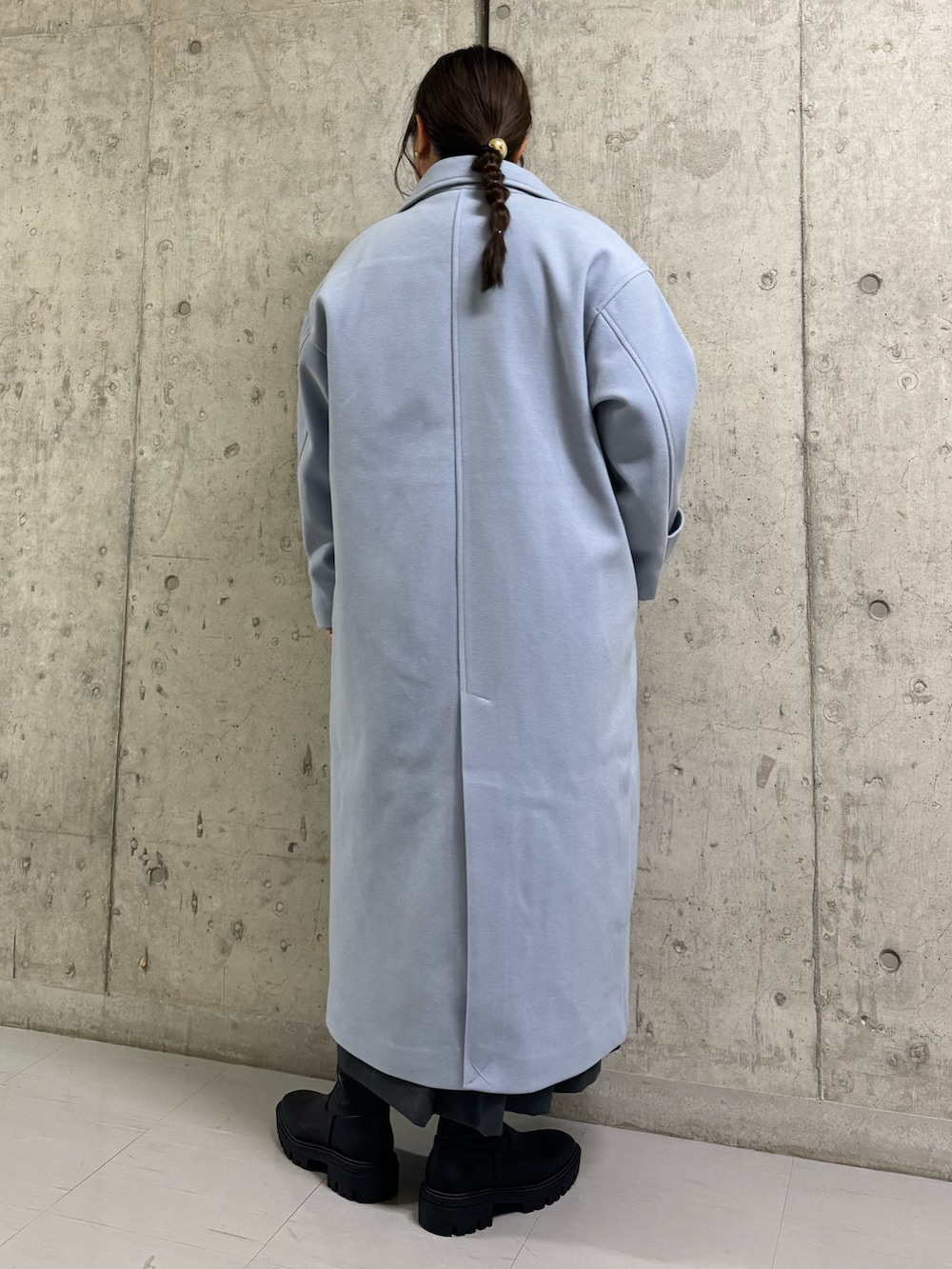 ブルー系のステンカラーコート、ブラック系のTシャツ/カットソー、グレー系のワンピースを着用したレディースの冬コーディネートの2枚目の写真