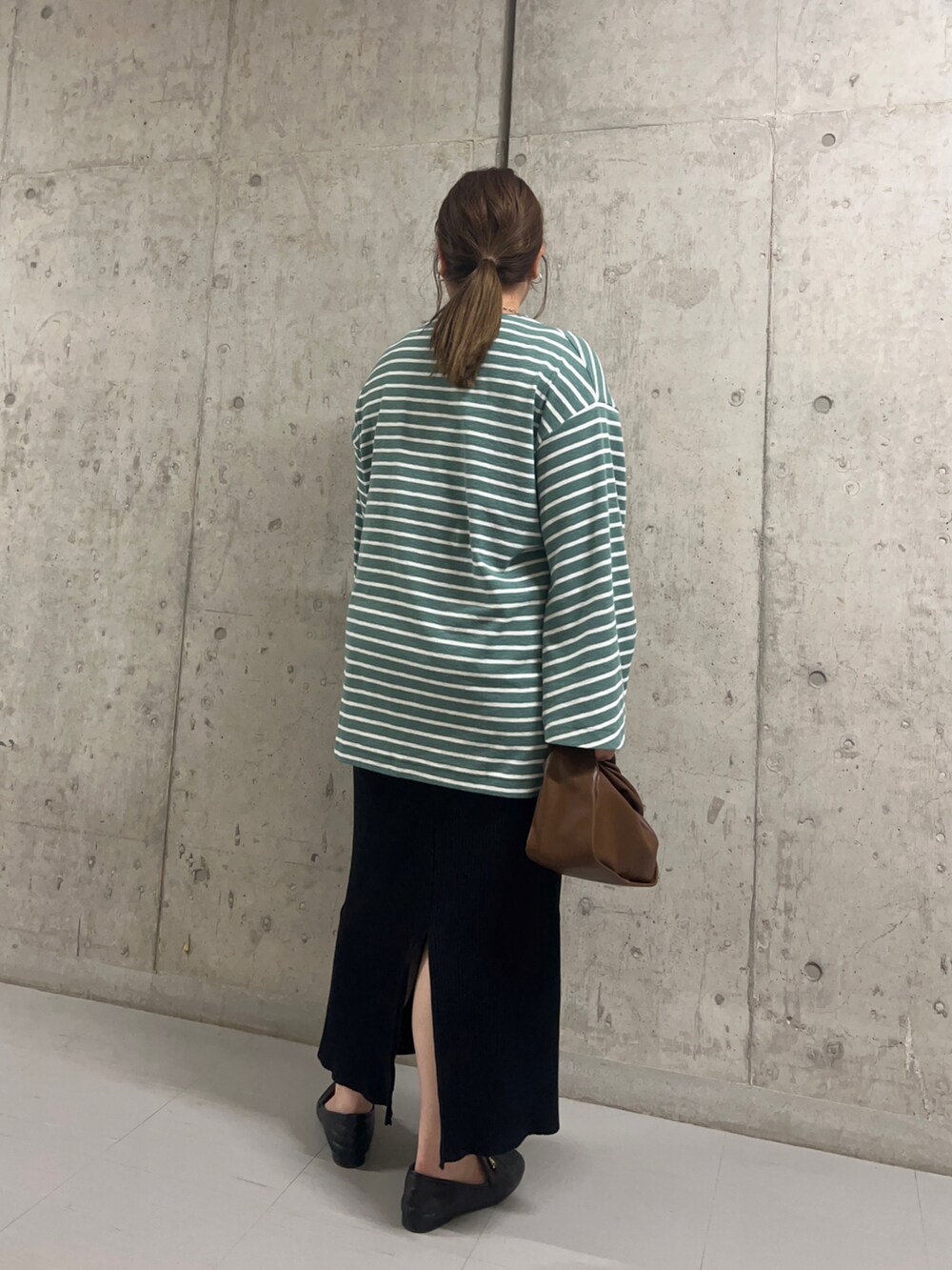 グリーン系のTシャツ/カットソー、ブラウン系のショルダーバッグ、ブラック系のスカートを着用したレディースの秋コーディネートの2枚目の写真