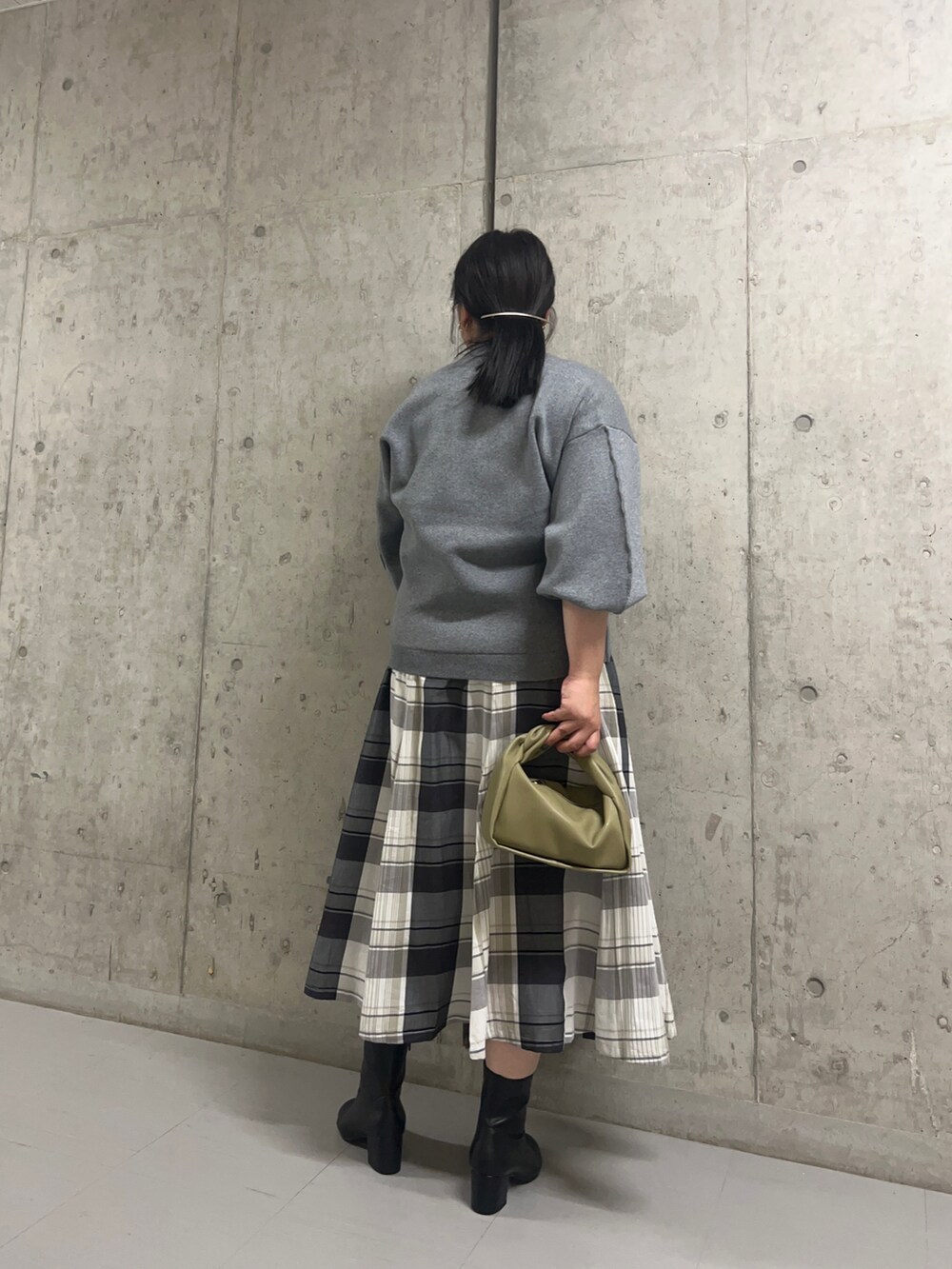 グレー系のニット/セーター、グリーン系のショルダーバッグ、ブラック系のスカートを着用したレディースの秋コーディネートの2枚目の写真