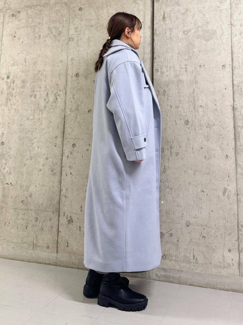 ブルー系のステンカラーコート、ブラック系のブーツ、グレー系のワンピースを着用したレディースの冬コーディネートの3枚目の写真